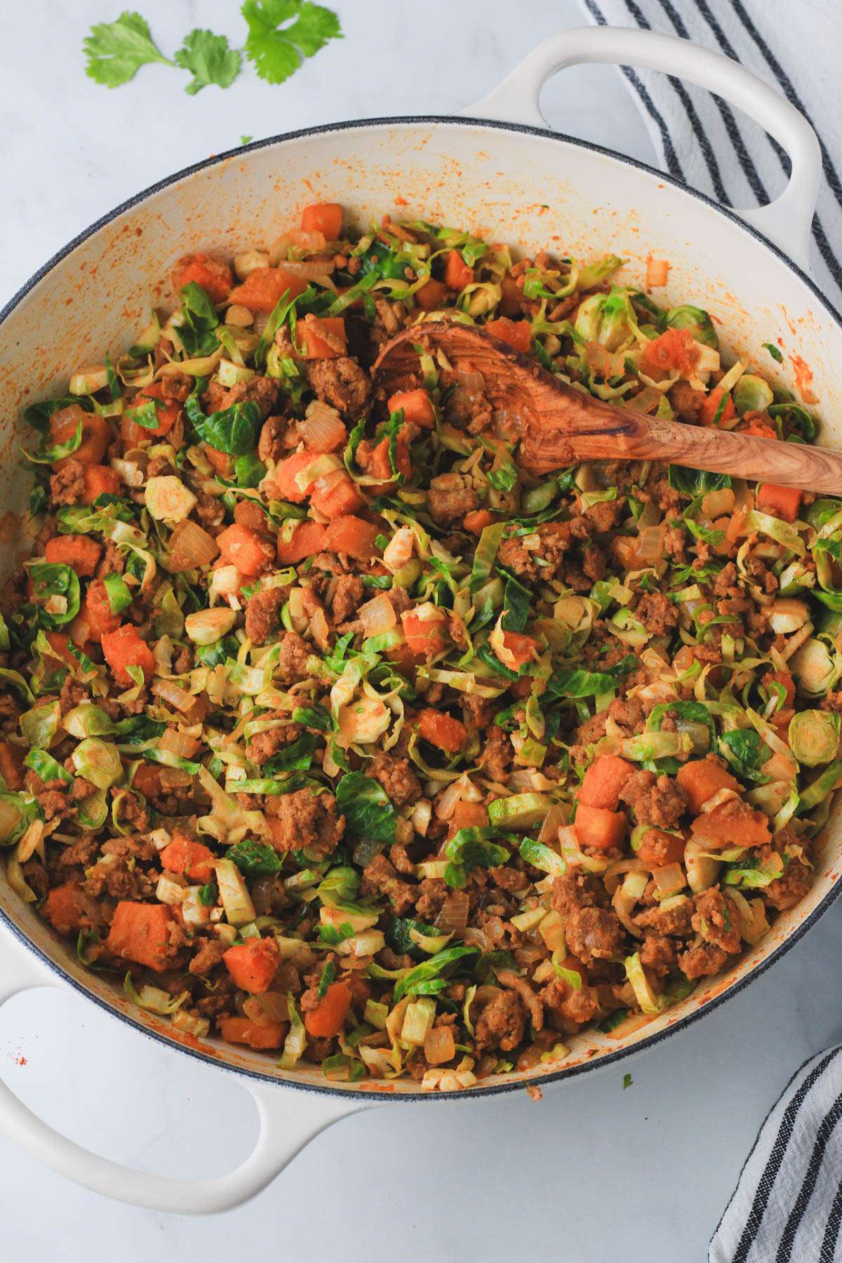 A white skillet with cooked turkey taco sweet potato dinner on a white counter.