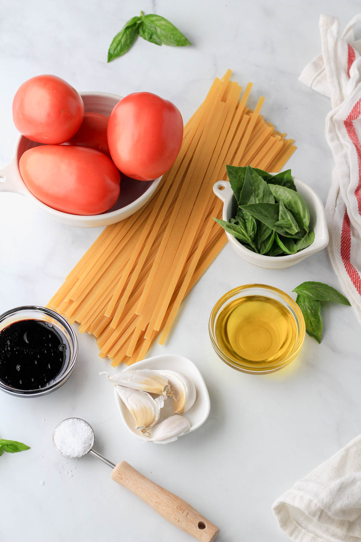 Ingredients for vegan bruschetta pasta on a white counter.