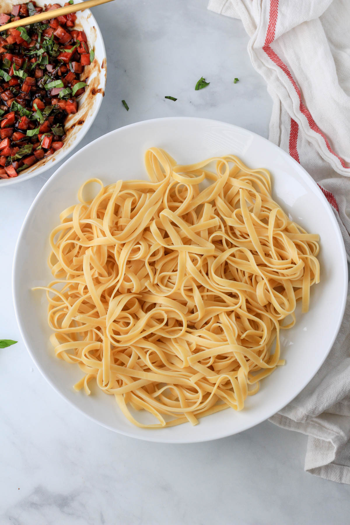 A large bowl of cooked pasta on a white counter.