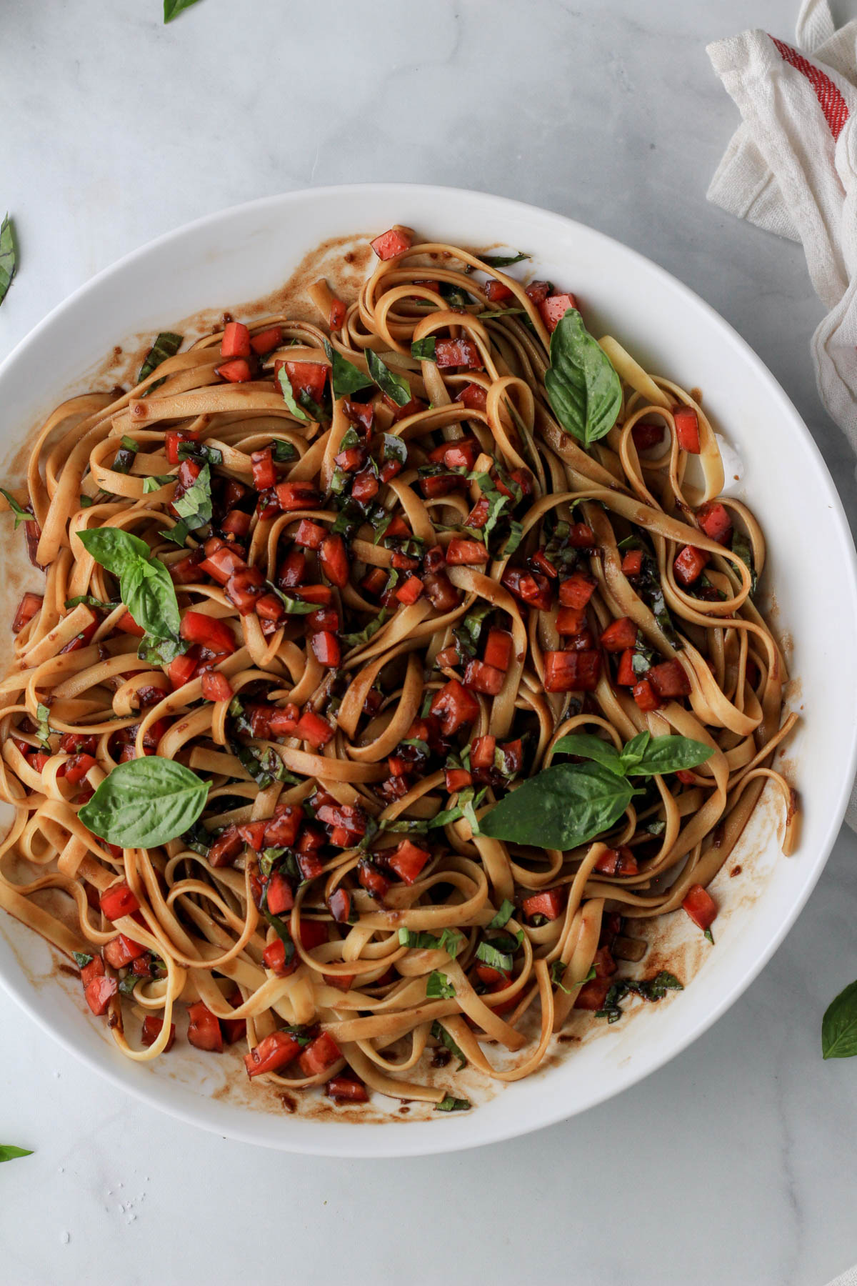 Vegan bruschetta pasta tossed together in a large white bowl.