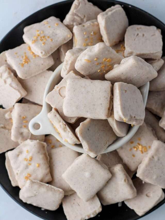 A black plate with a small bowl in the middle filled with white chocolate pumpkin spice graham crackers.