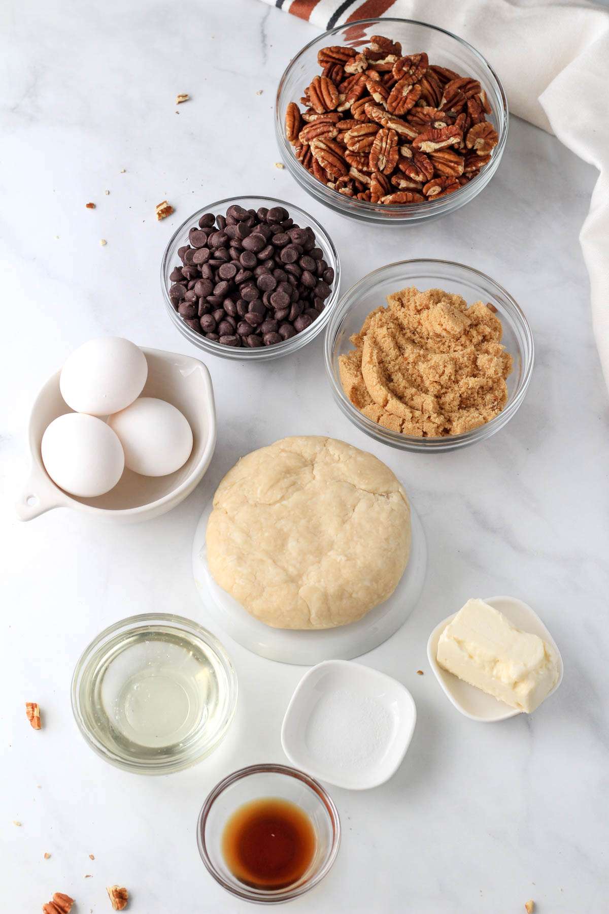 Ingredients for chocolate pecan pie on a white counter.