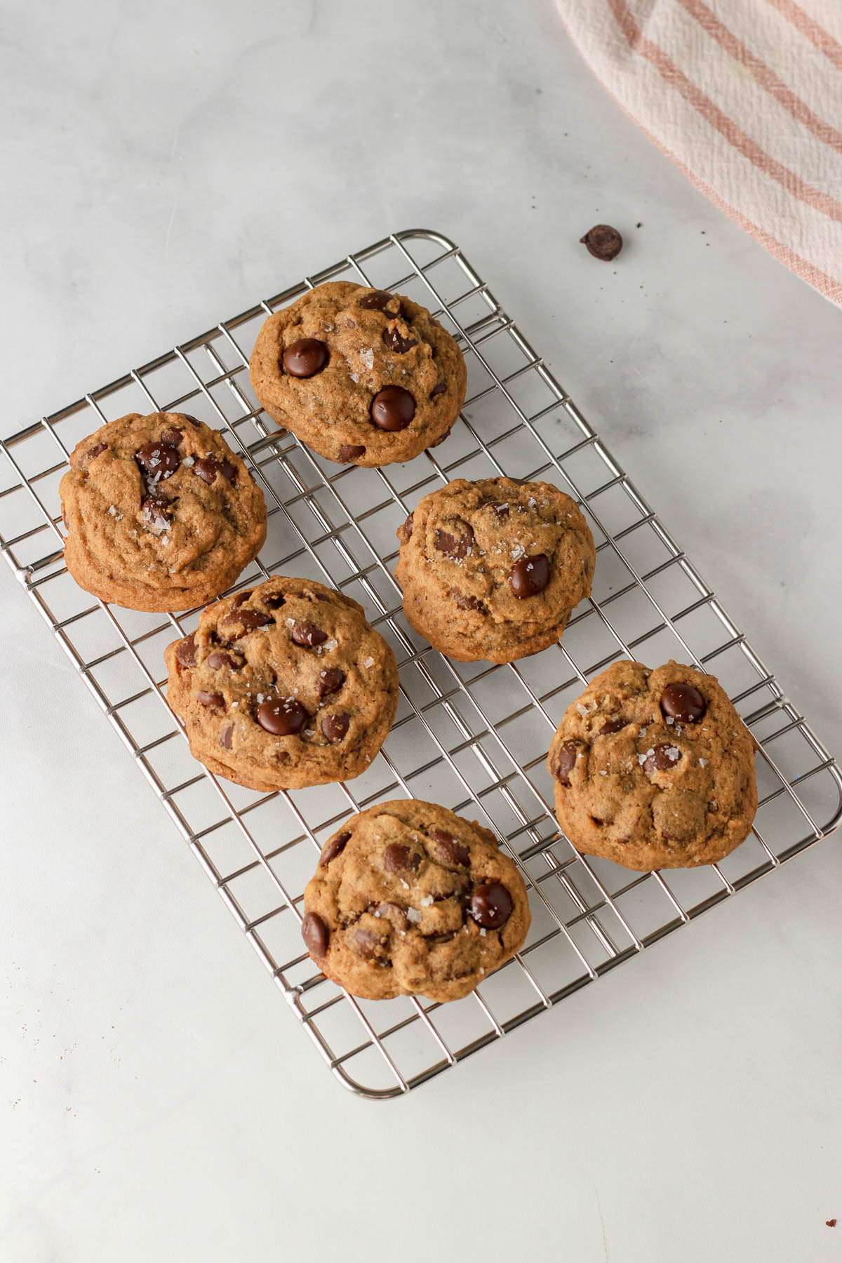 A small wire cooling rack with espresso chocolate chip cookies on a white counter.