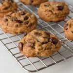 A side angle picture of an espresso chocolate chip cookie topped with flaky sea salt.