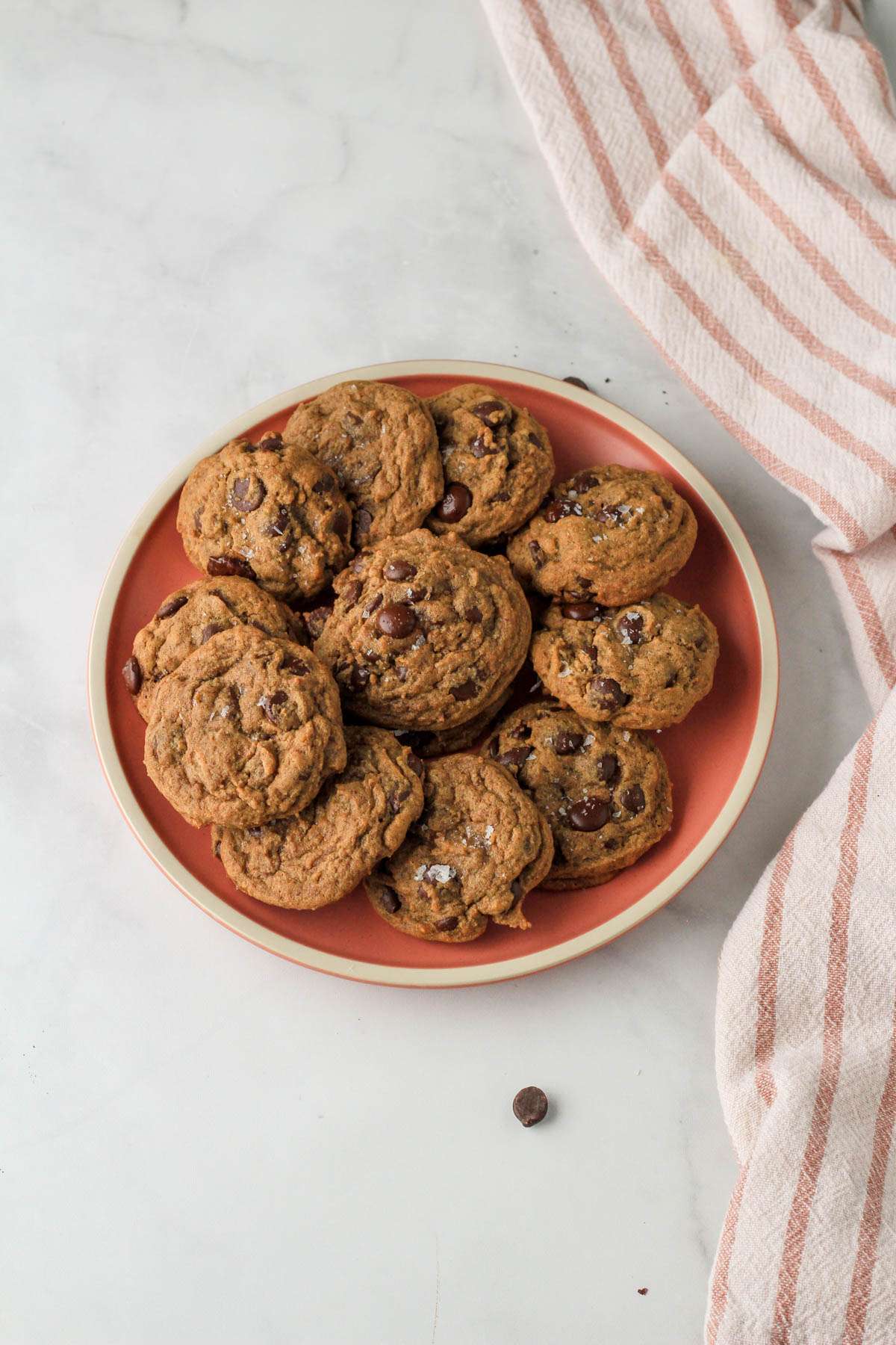 A pink plate topped with fresh espresso chocolate chip cookies on a white counter.