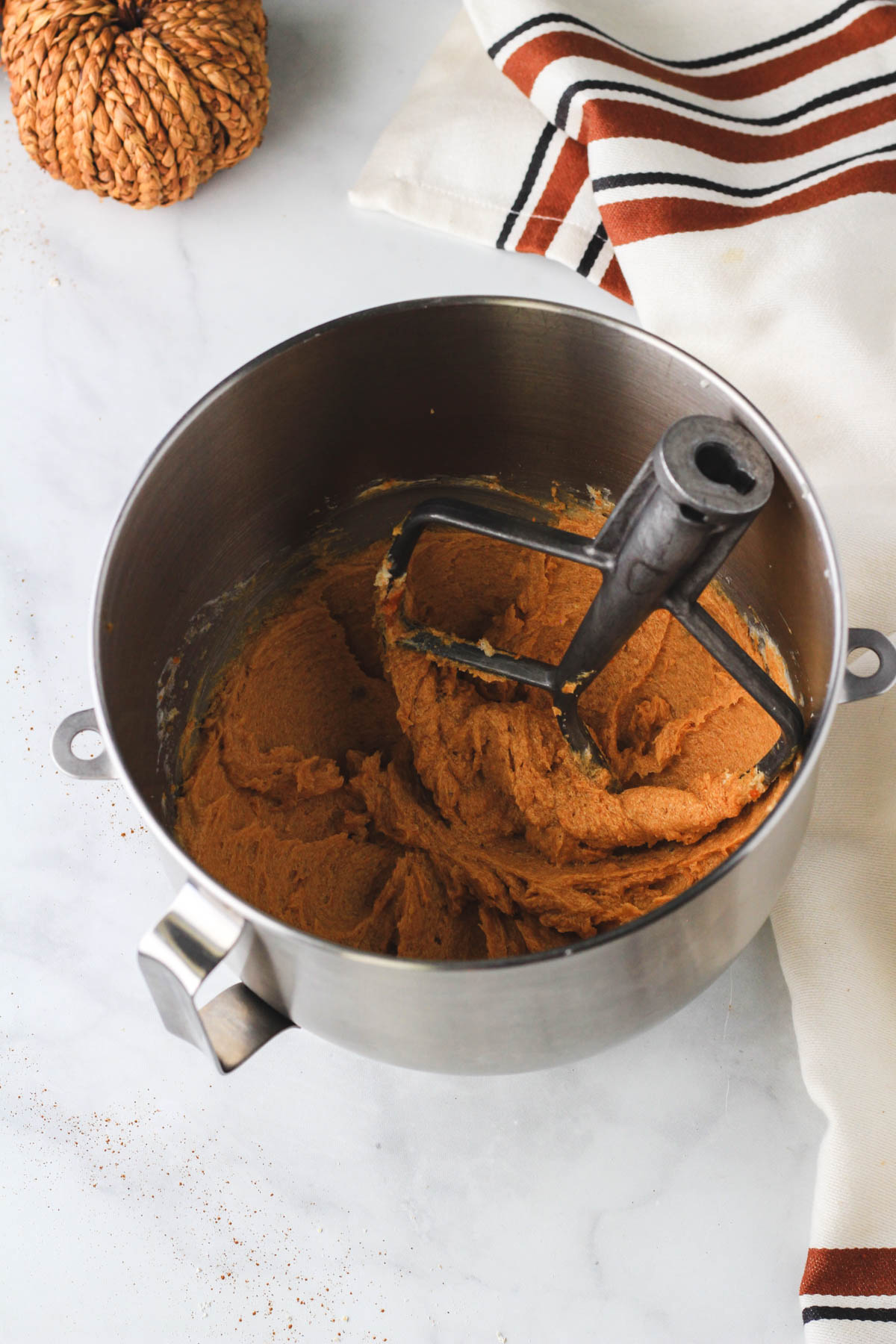 A silver mixing bowl with the paddle attachment and the wet ingredients mixed together.