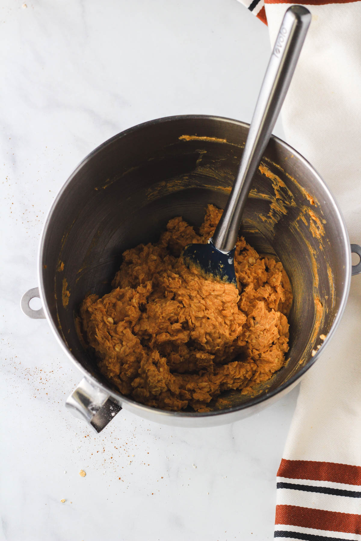 A rubber spatula in a silver mixing bowl after mixing the dry ingredients into the batter.