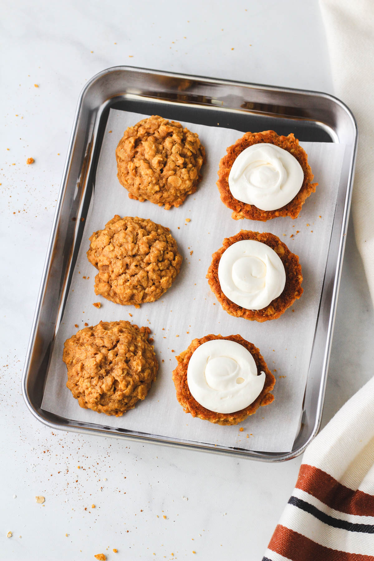 A small rimmed cookie sheet with pumpkin spice oatmeal cookies after adding the icing.