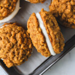 A close up of dairy-free pumpkin spice oatmeal cream pie cookies with one on the side.