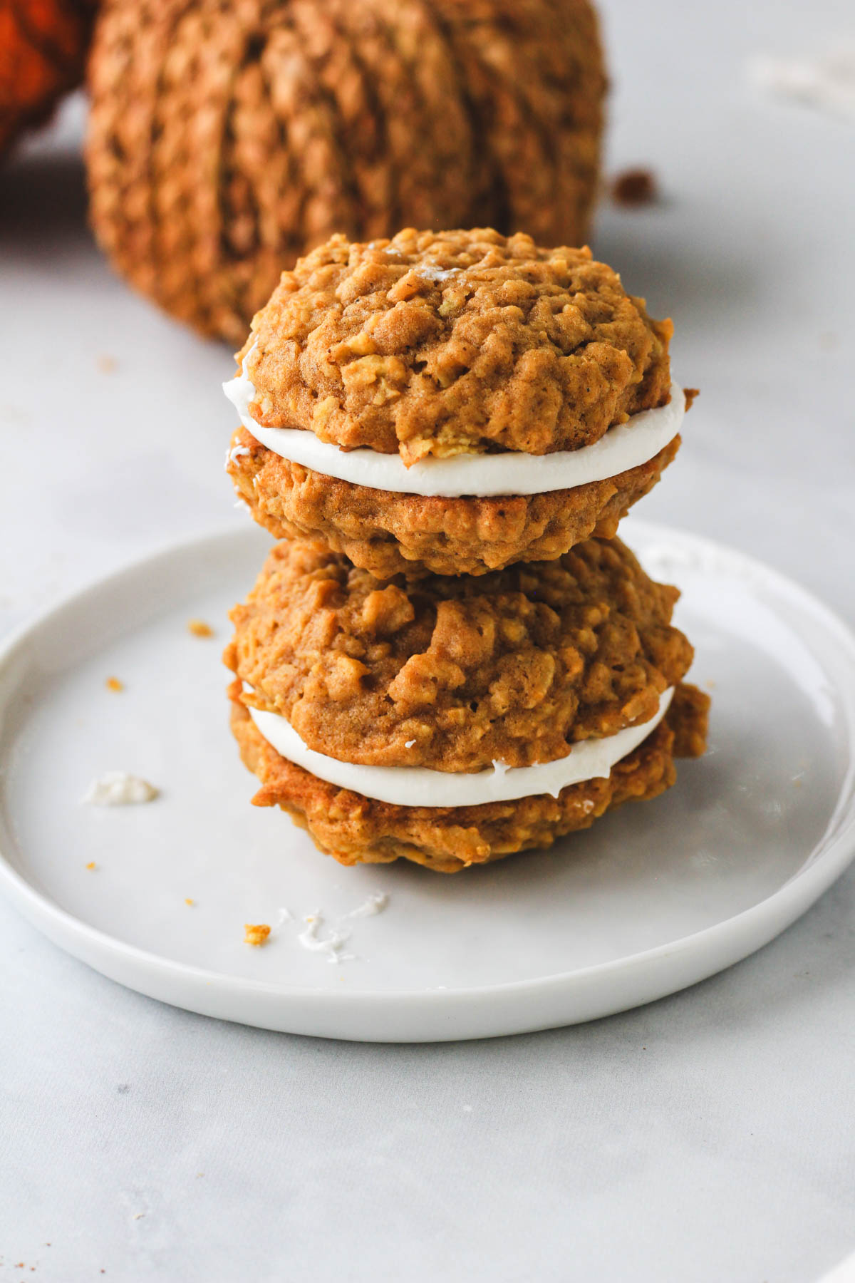 A small white plate with a stack of two dairy-free pumpkin spice oatmeal cream pies.