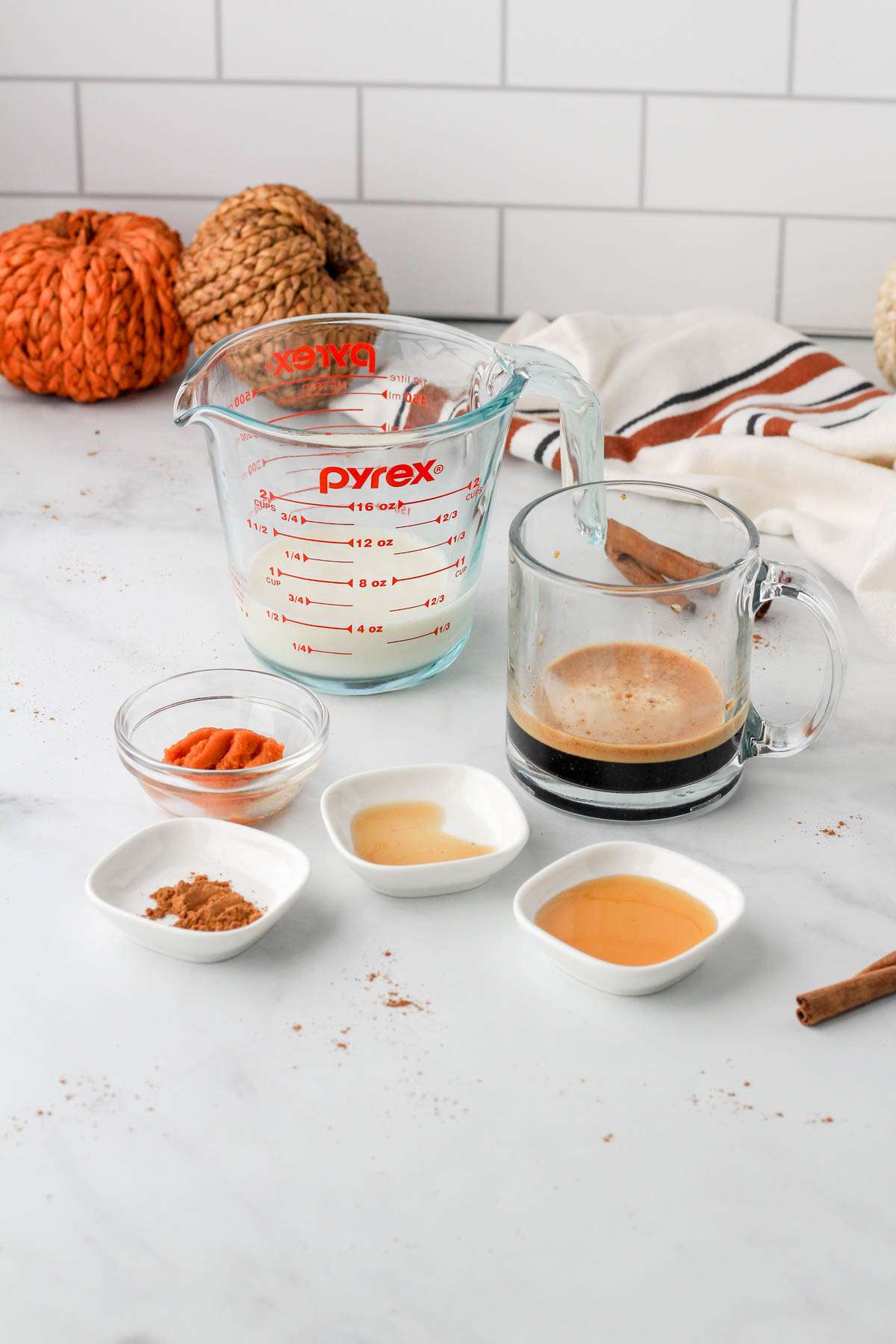 Ingredients for a pumpkin spice latte on a white counter.