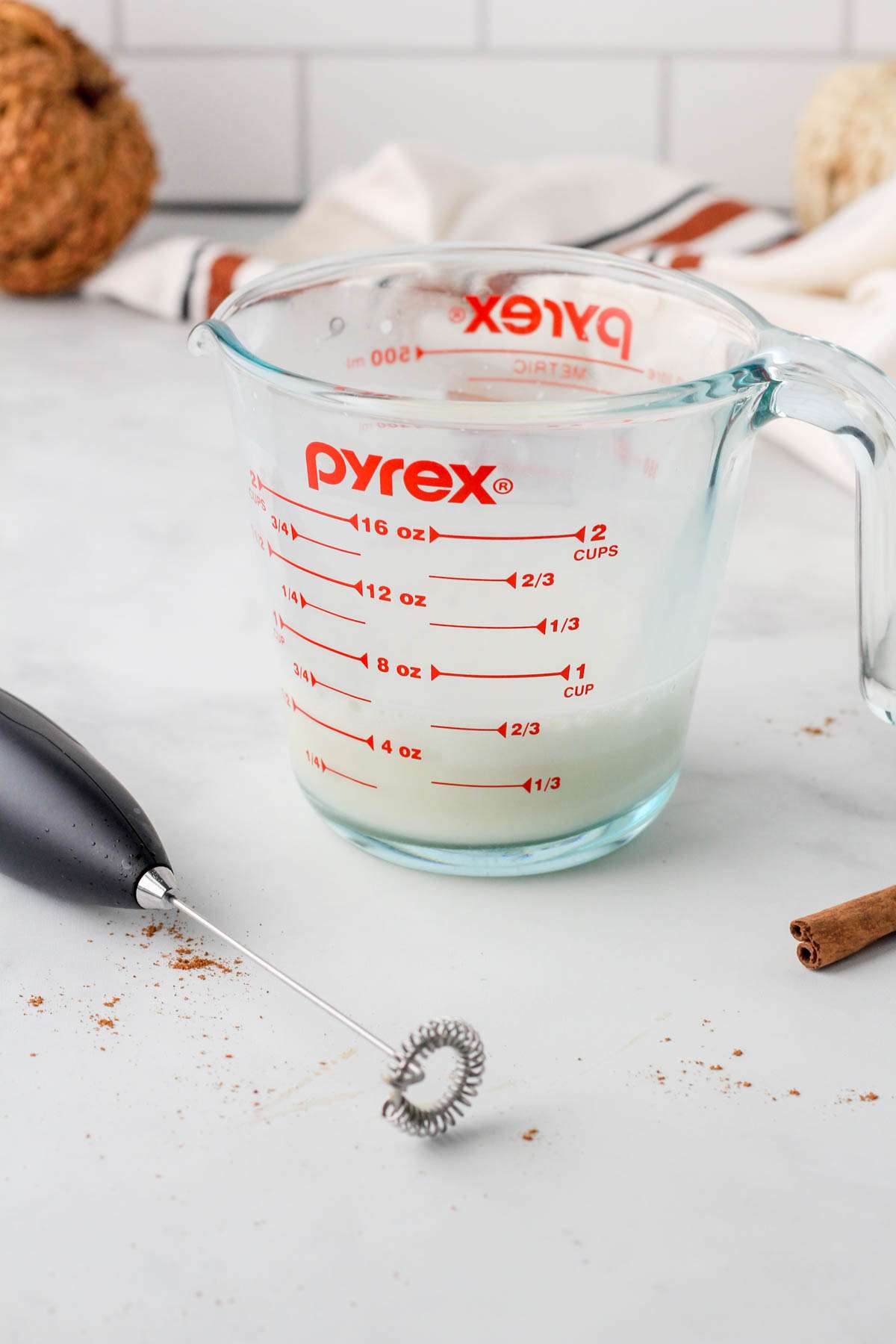 Warmed and frothed oat milk in a glass liquid pyrex cup.