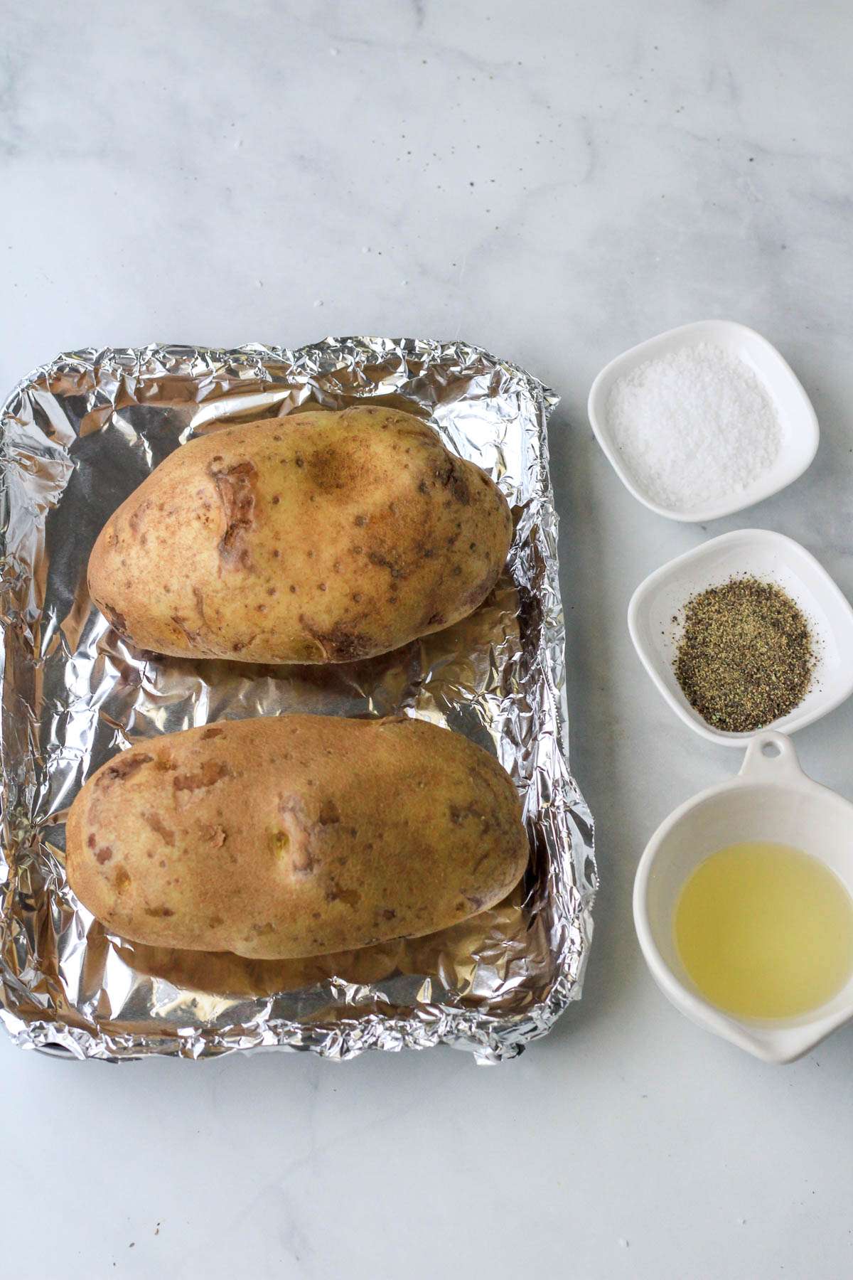 Ingredients for basic baked potatoes on a white counter.