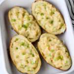 A close up of four vegan twice baked potatoes in a white baking dish.