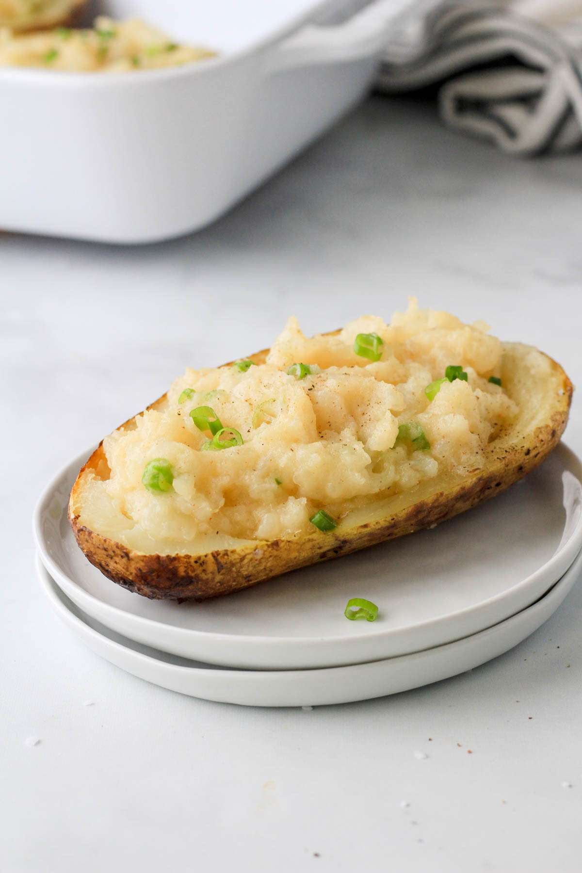 A stack of two small white plates with a vegan twice baked potato on top.