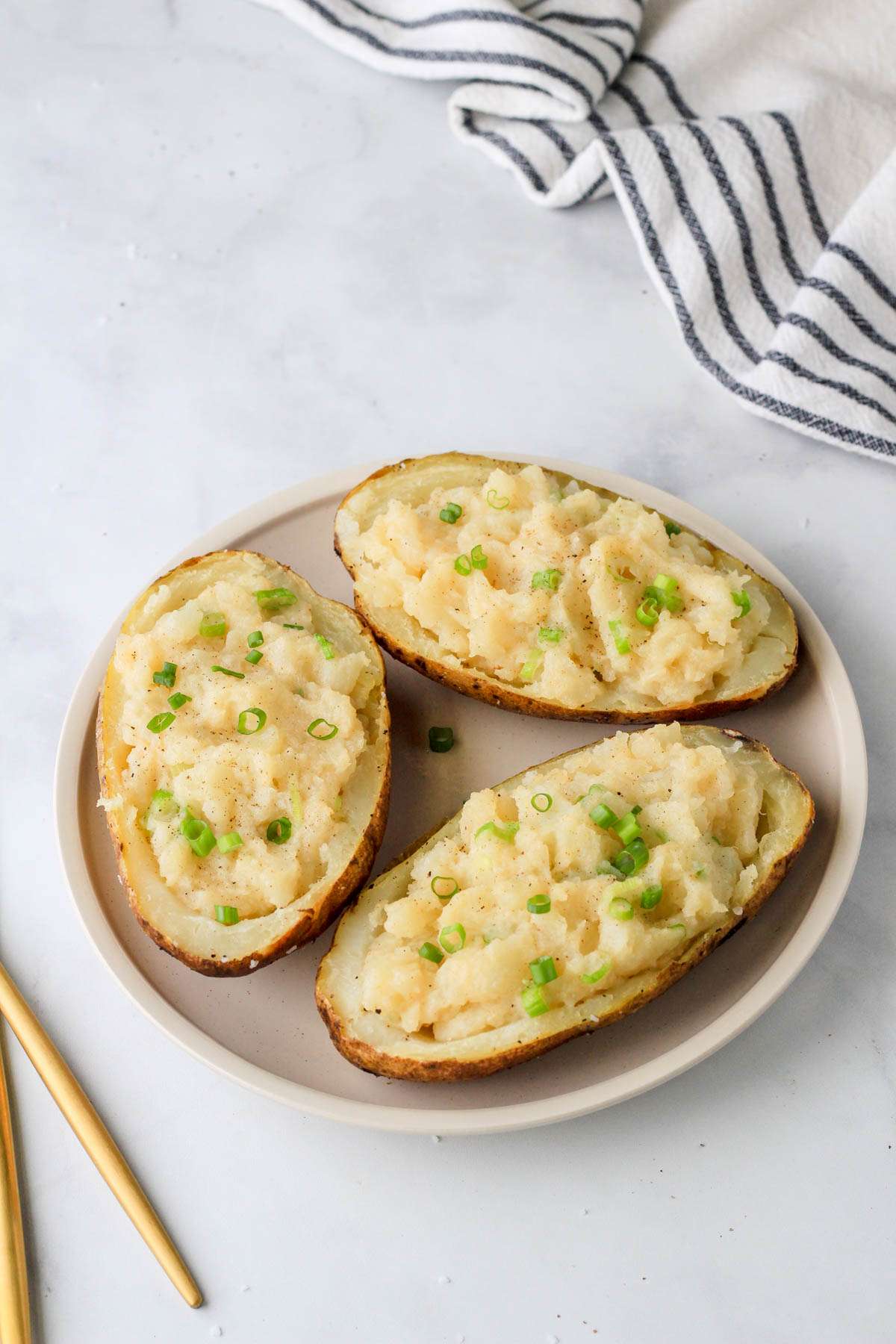 A cream colored plate with three vegan twice baked potatoes on a circle around the plate.