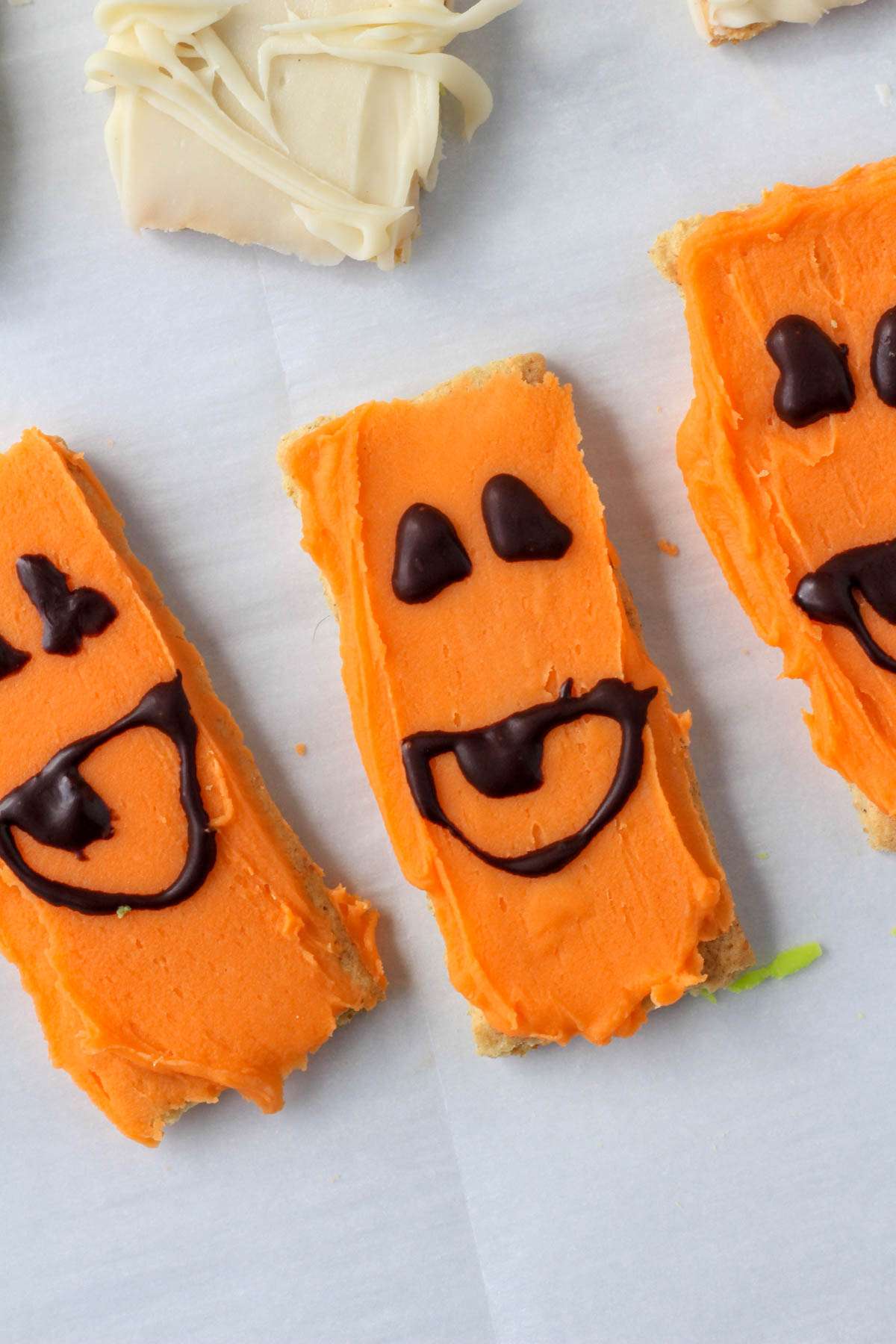 Orange white chocolate dipped graham crackers decorated to look like pumpkins.