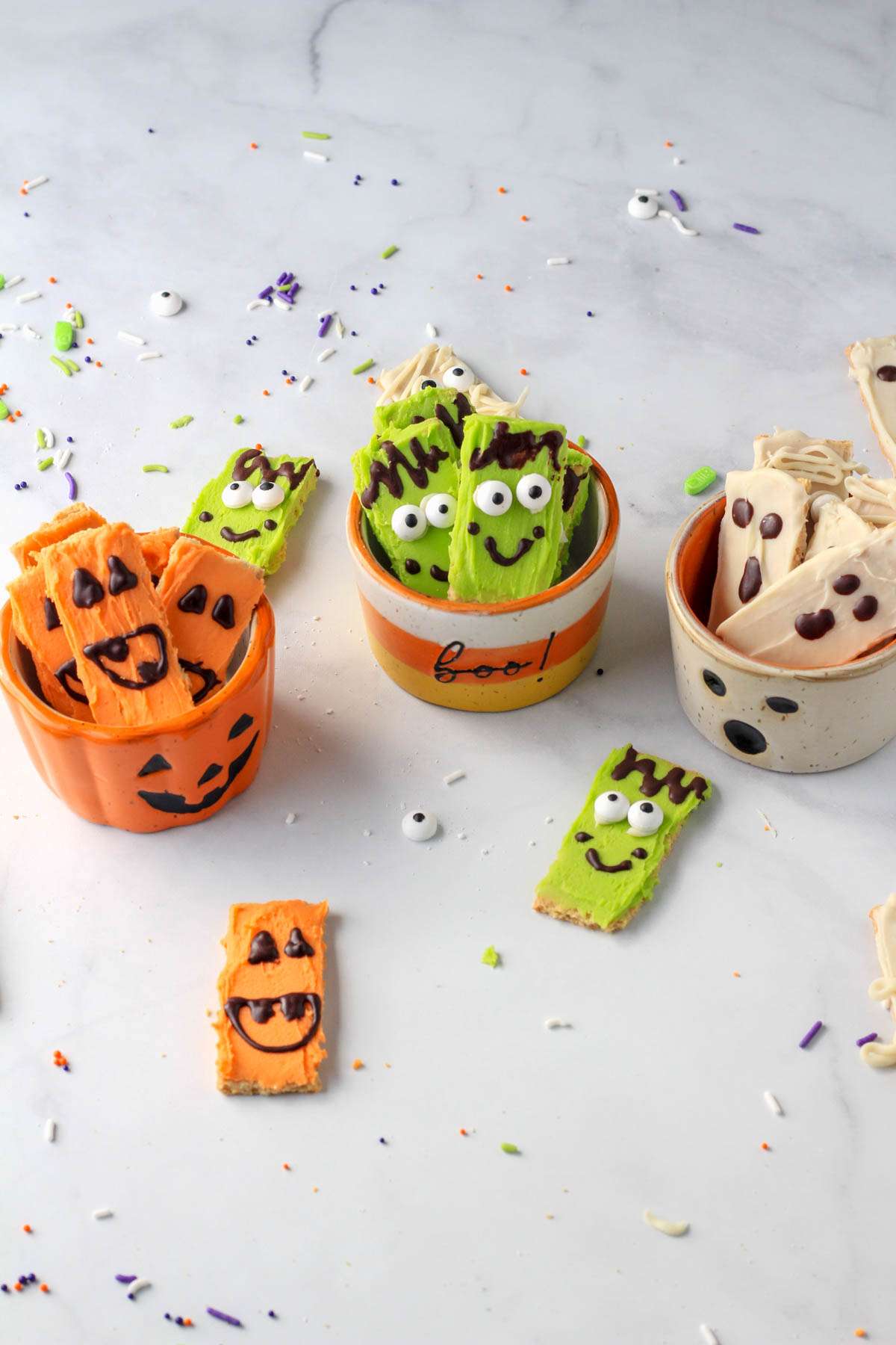 Halloween decorated white chocolate dipped graham crackers on a white counter.