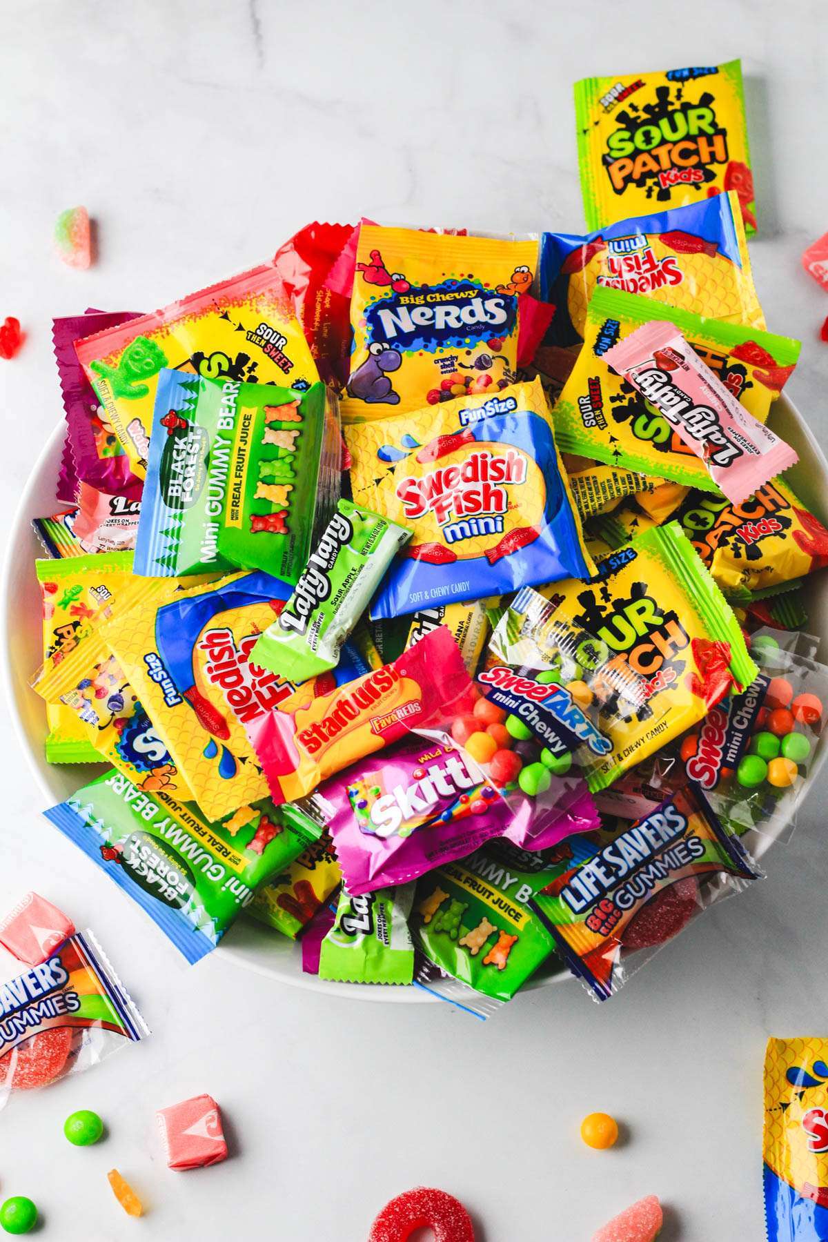 A bowl filled with dairy-free candy and pieces of dairy-free candy around it.