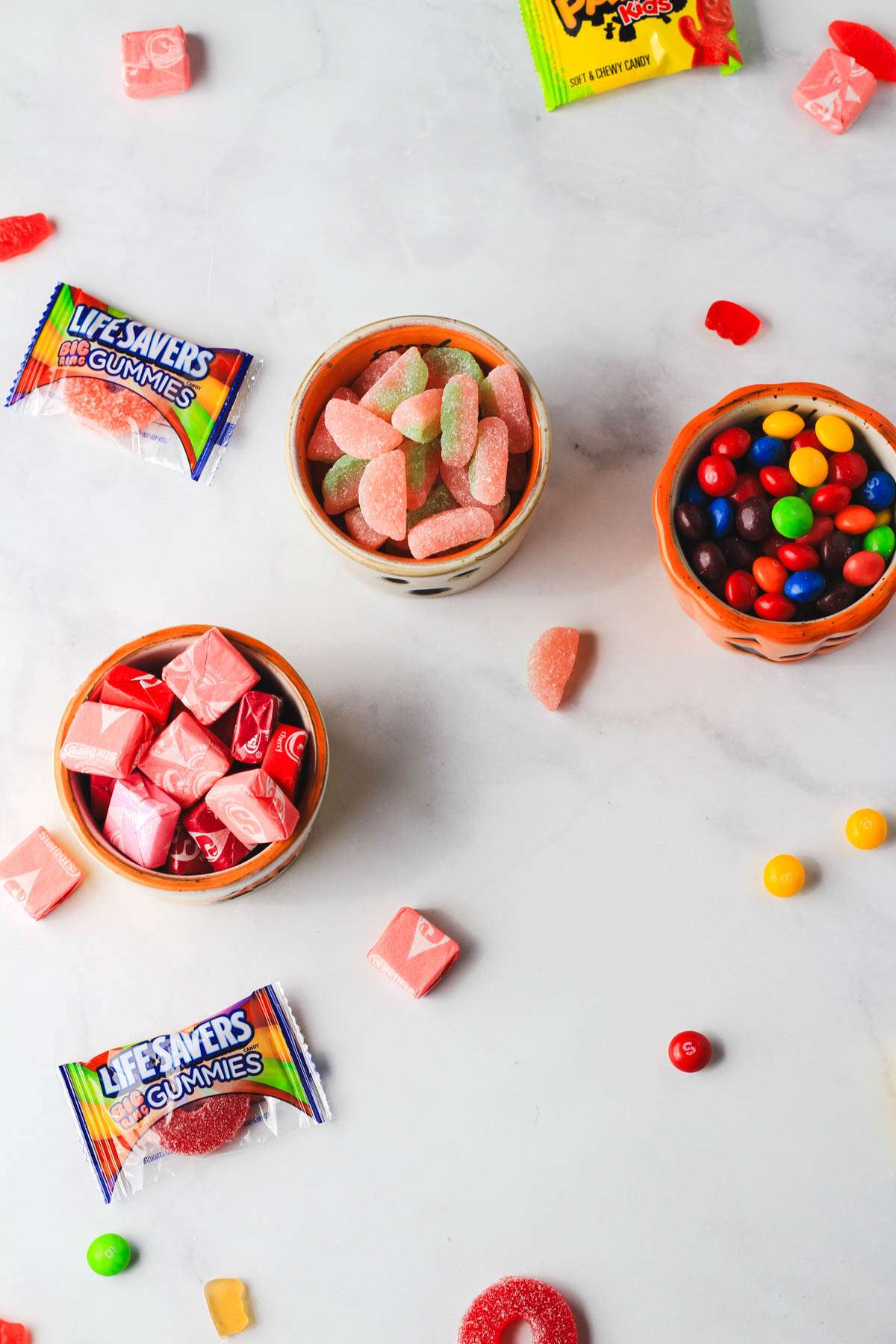 A top down picture of dairy-free candy in bowls on a white counter.