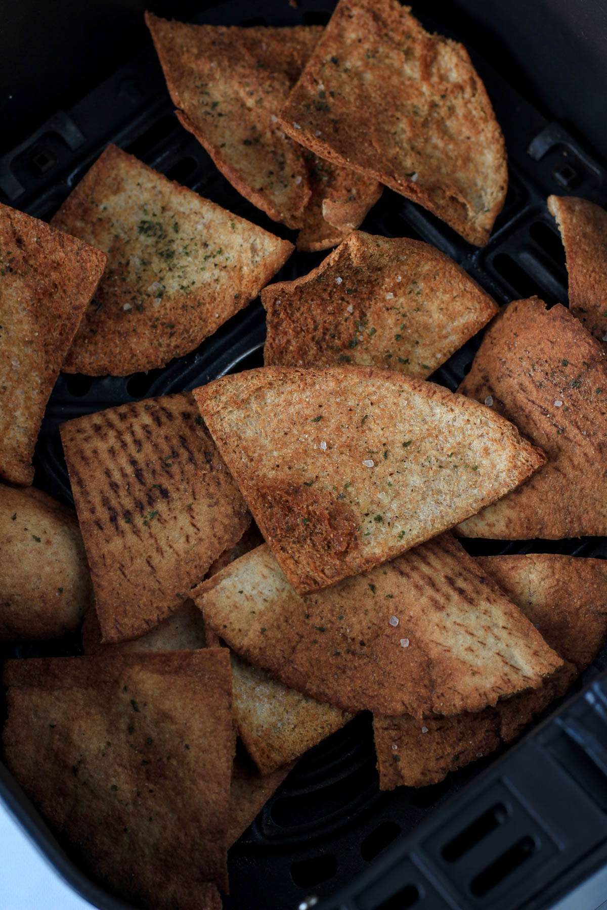 An air fryer basket with pita chips after cooking.
