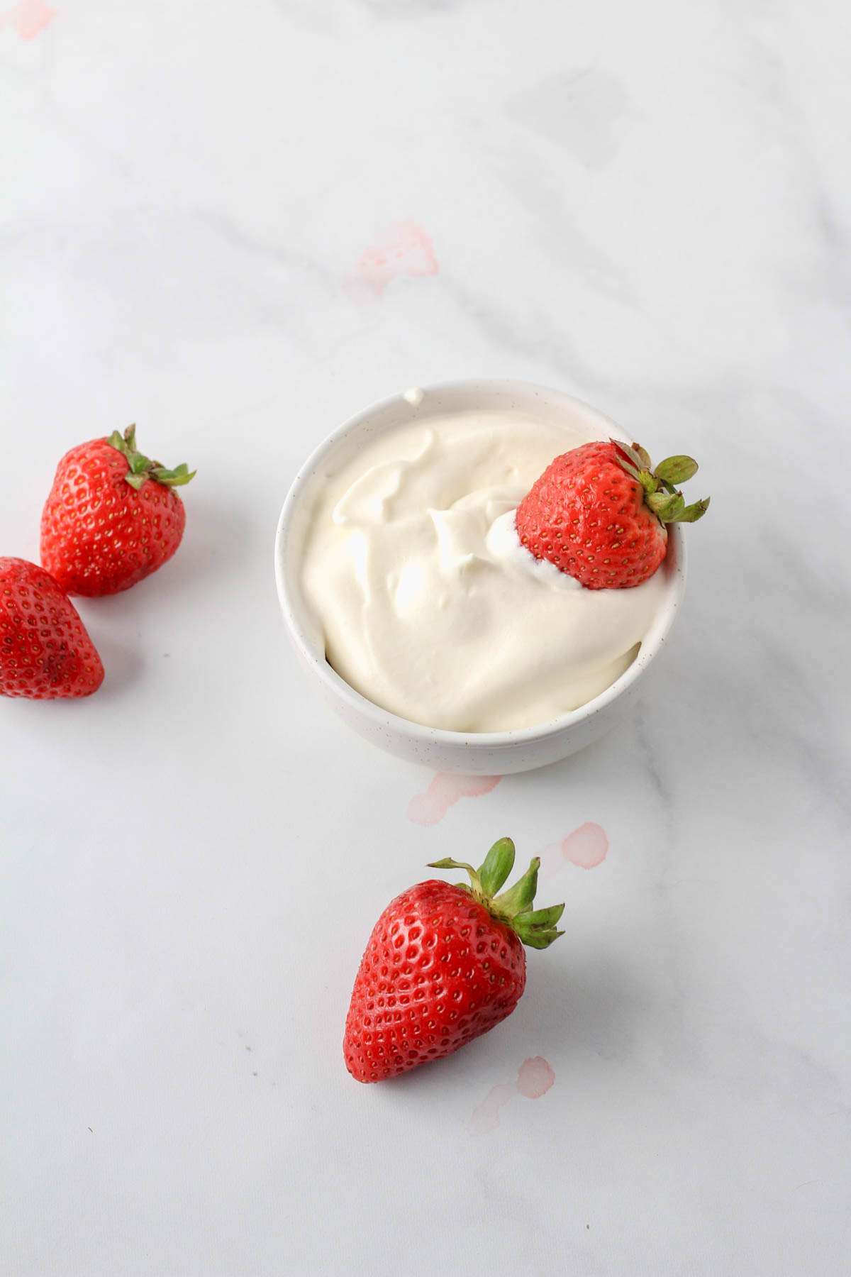 A top down picture of strawberries around a bowl of vegan whipped cream made with country crock plant cream.