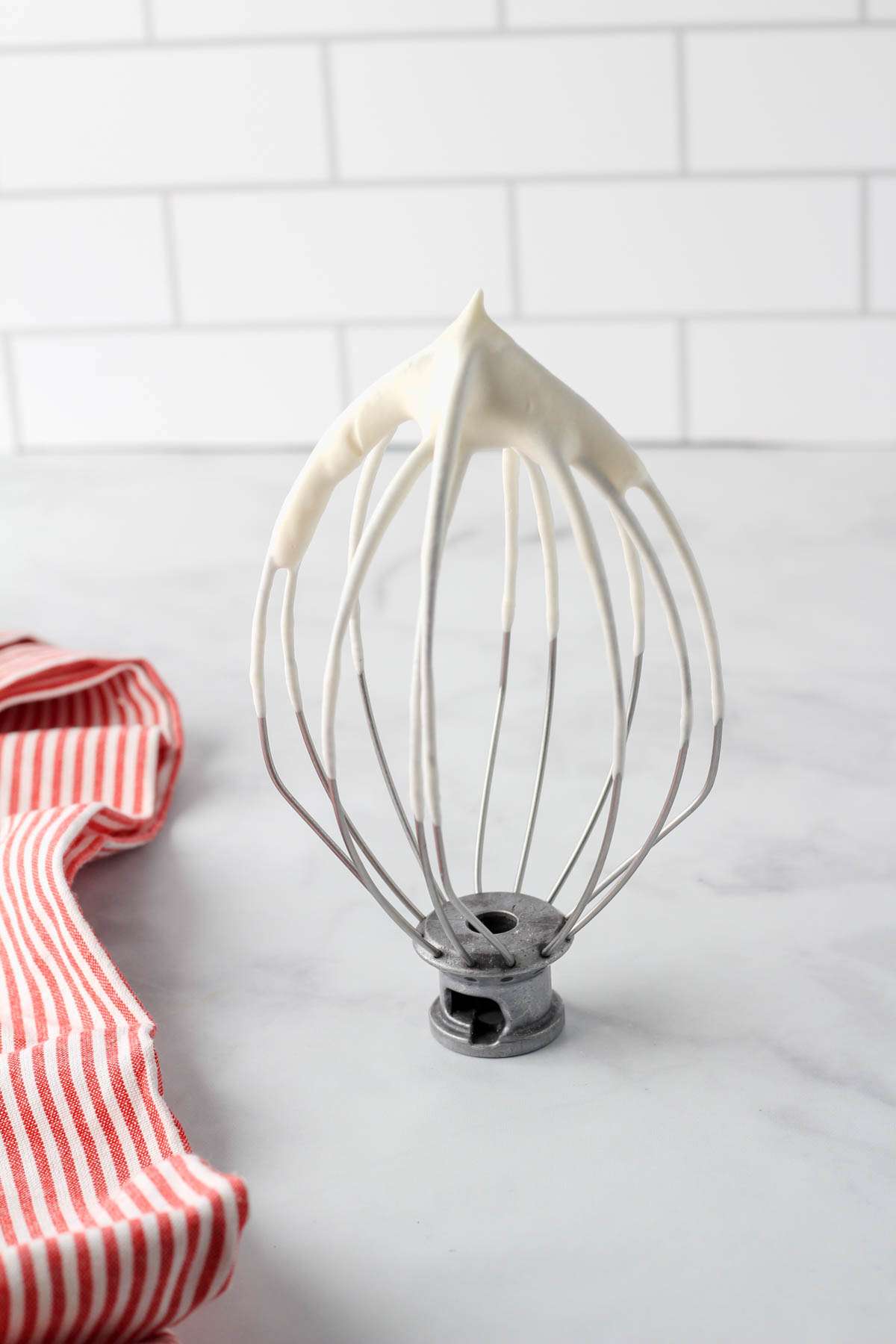 A silver whisk attachment topped with vegan whipped cream.