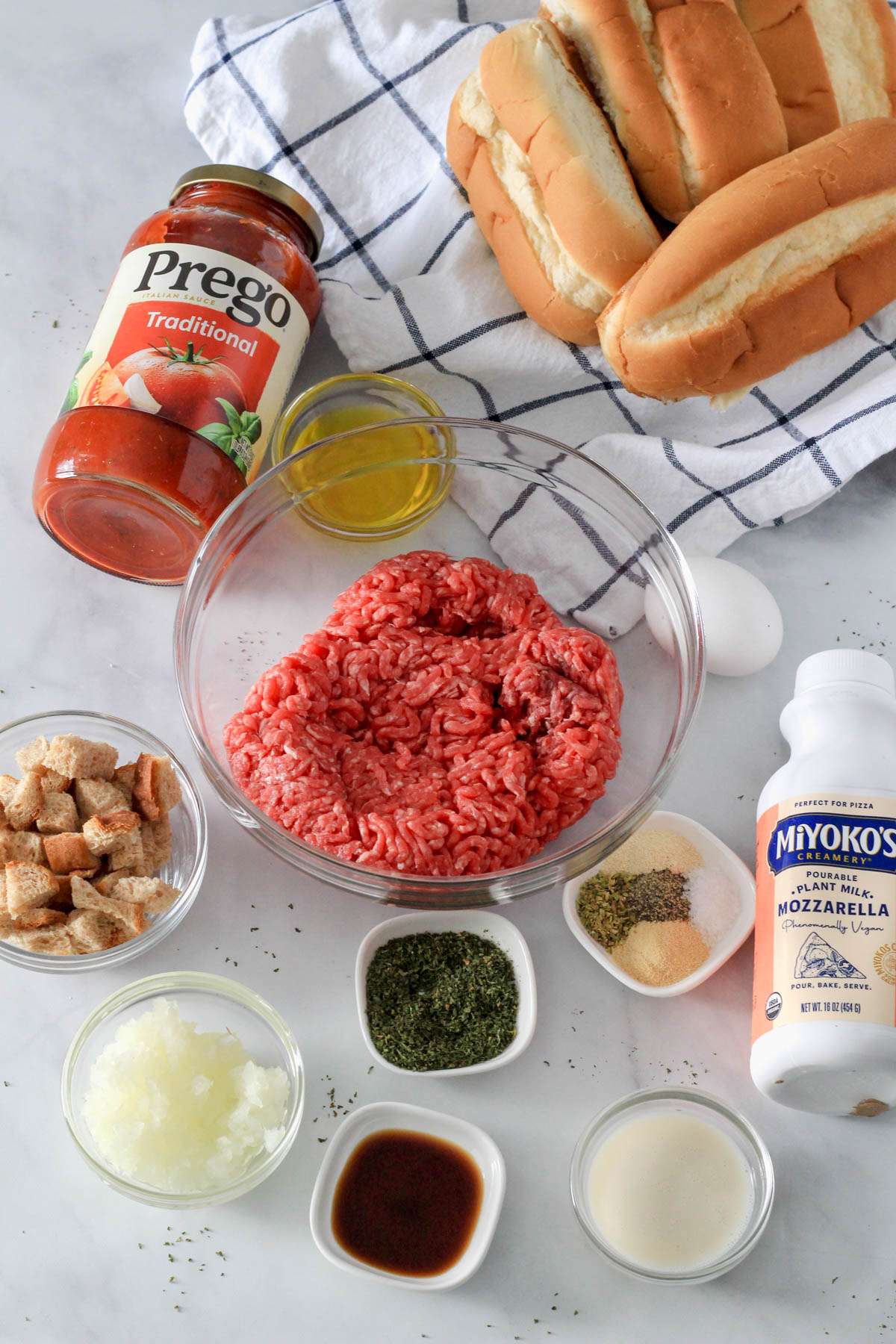 Ingredients for dairy-free meatball subs on a white counter.