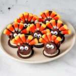 A close up of a plate with seven dairy-free chocolate turkey cookies from Oreos.