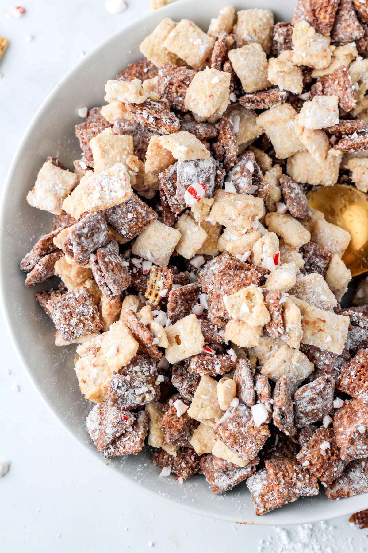 A close up shot of the left side of a white bowl filled with dairy-free peppermint bark muddy buddies.