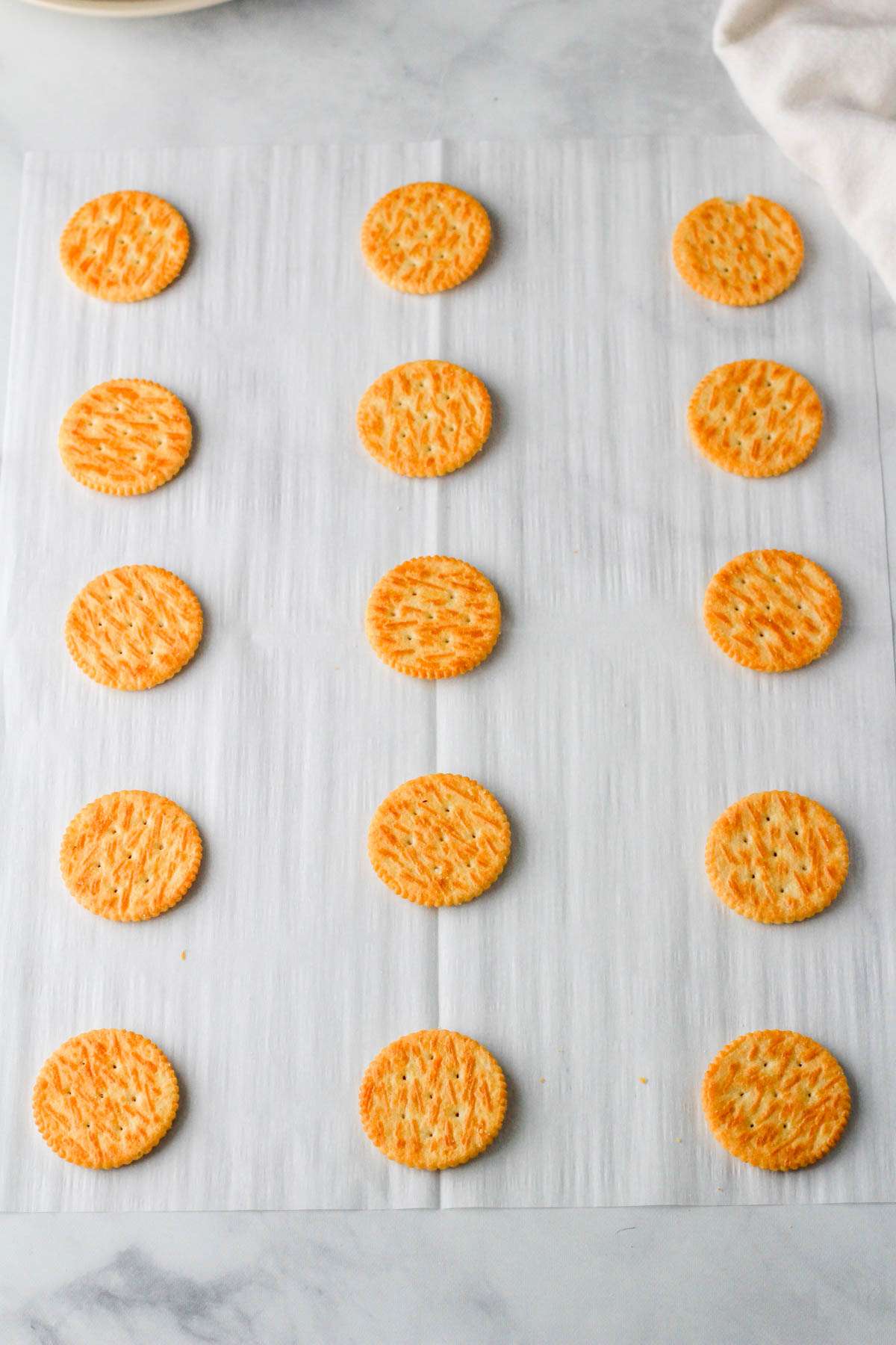 A parchment paper with Ritz crackers top side down.