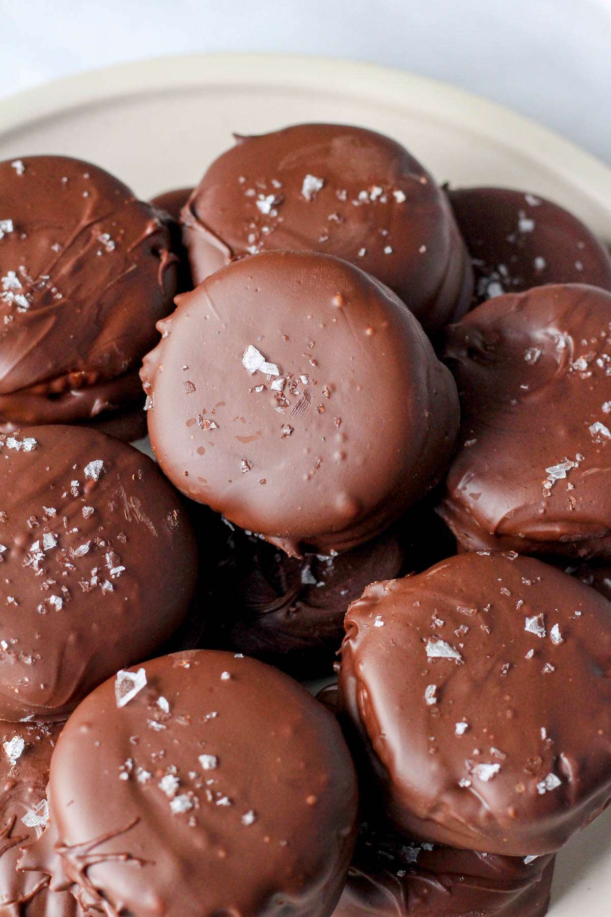 A close up of vegan chocolate peanut butter Ritz cookies topped with flaky sea salt.