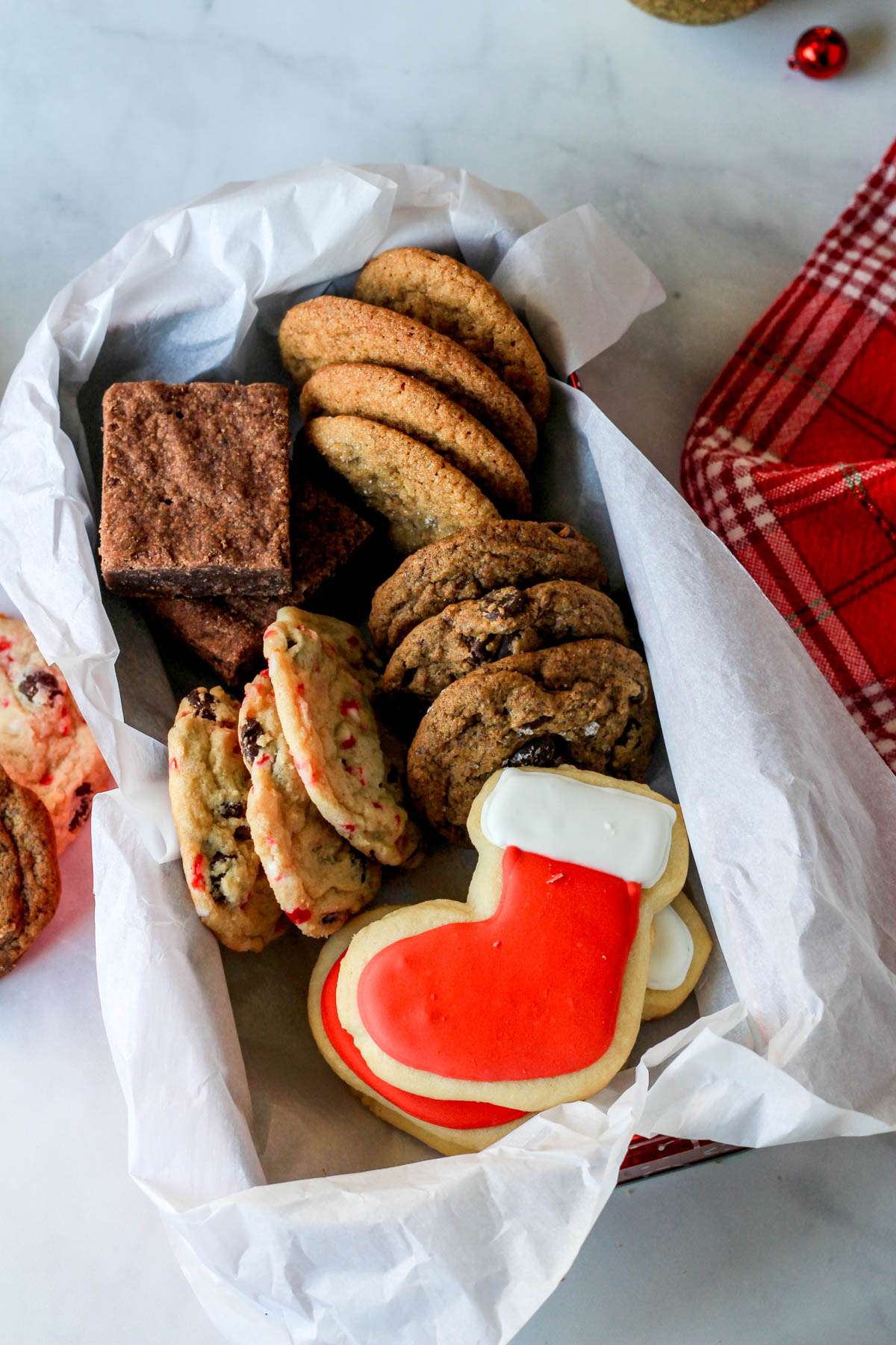A red box lined with parchment paper and filled with different cookies.