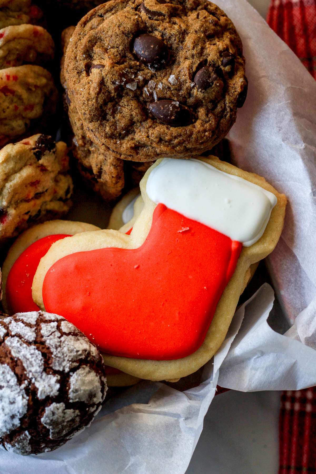 A close up of a dairy-free sugar cookie ice with red and white icing in a parchment paper lined box.