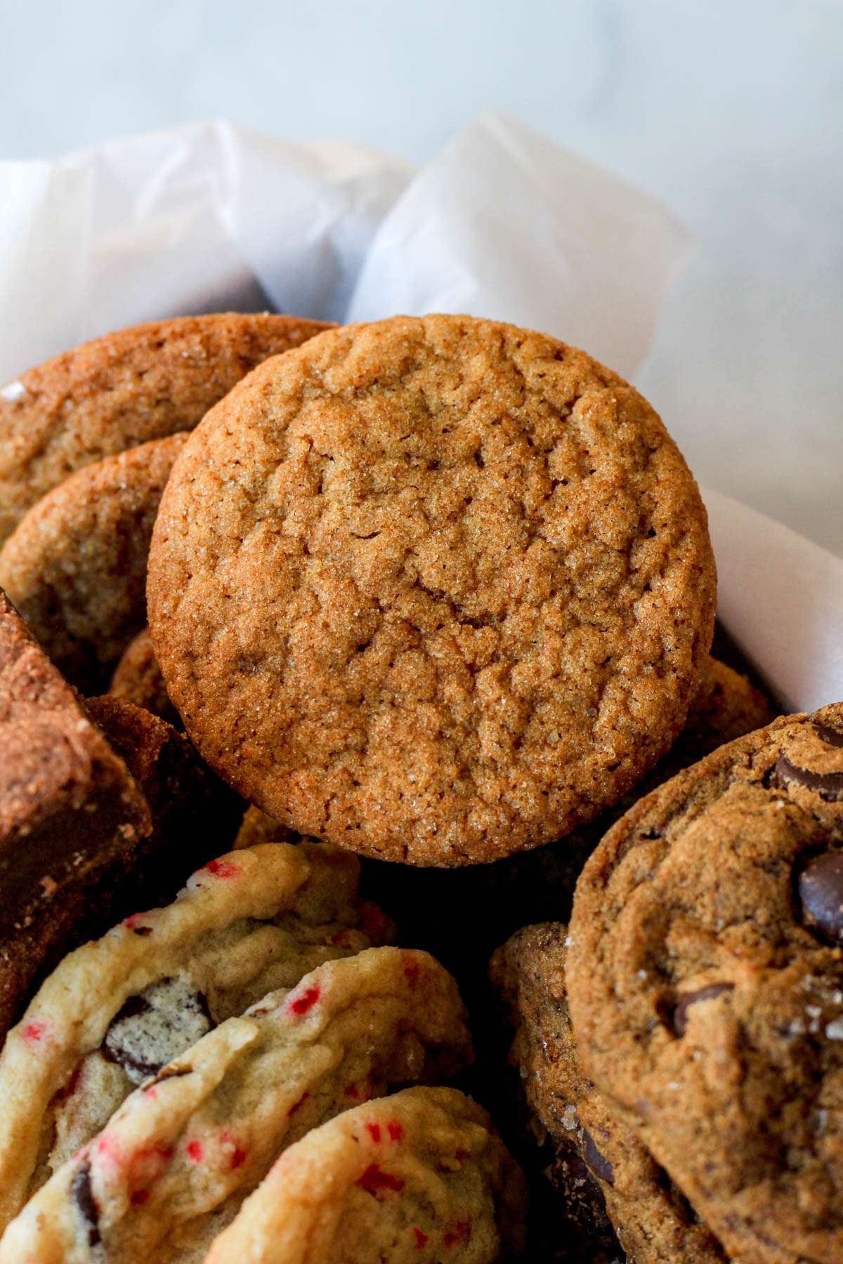 A close up of a soft ginger cookie in a parchment paper lined box.