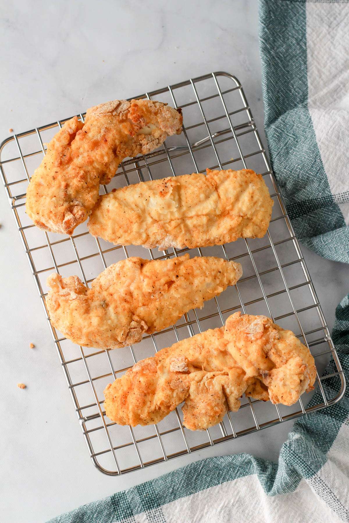 A cooling rack with four air fryer chicken tenders after cooking in the air fryer.
