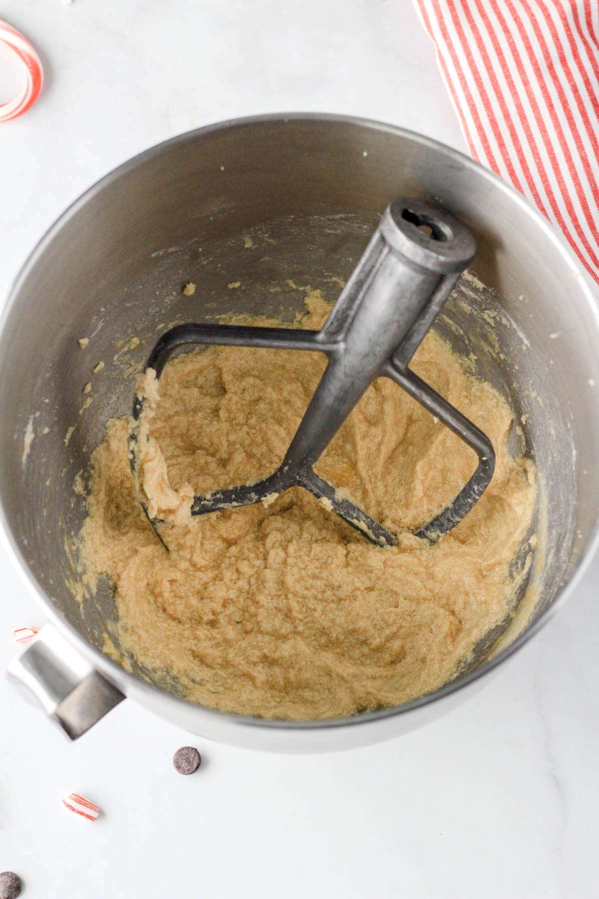 A silver bowl with a paddle attachment with the wet ingredients creamed together.
