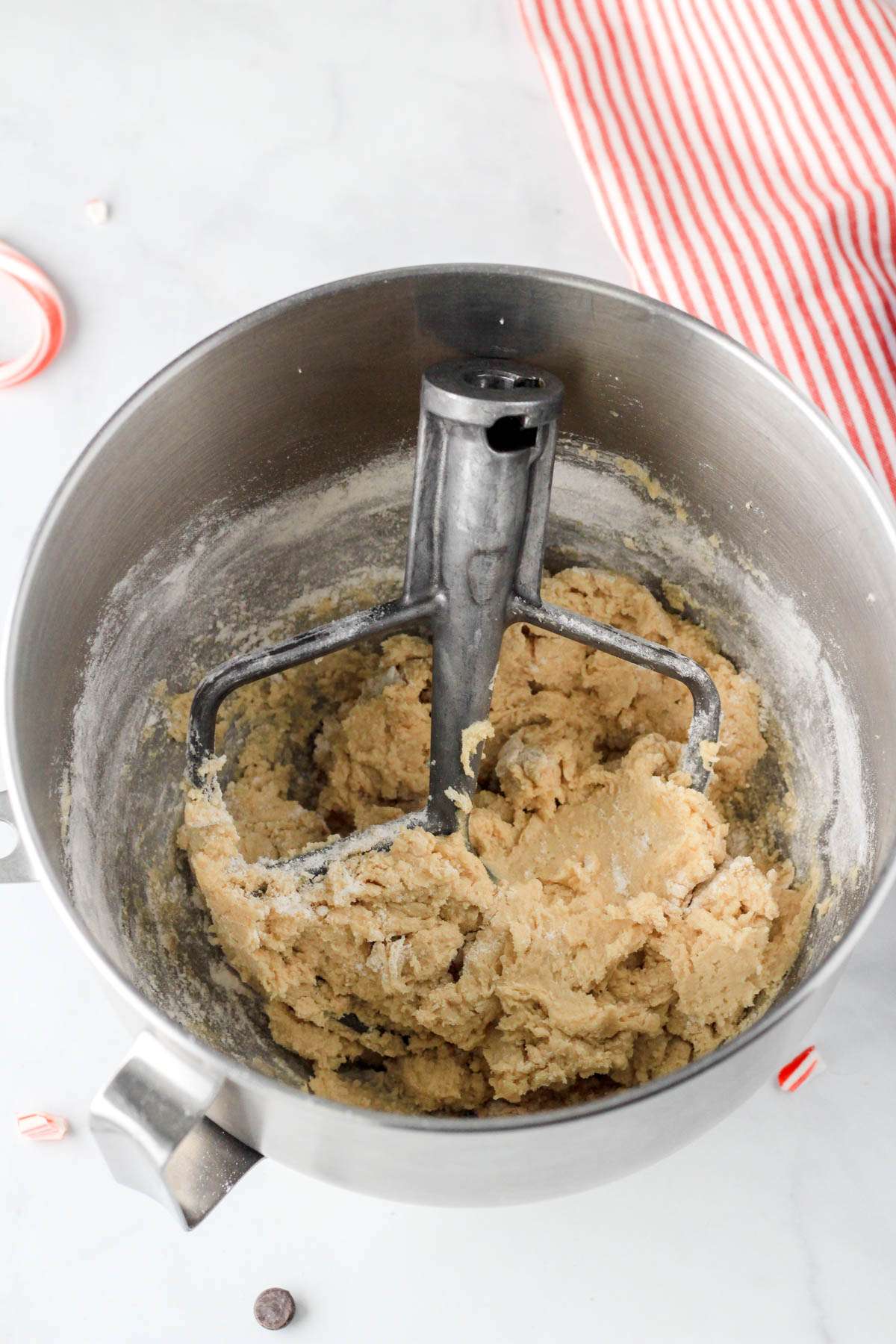 A silver bowl with a paddle attachment and peppermint cookie dough after adding the dry ingredients.