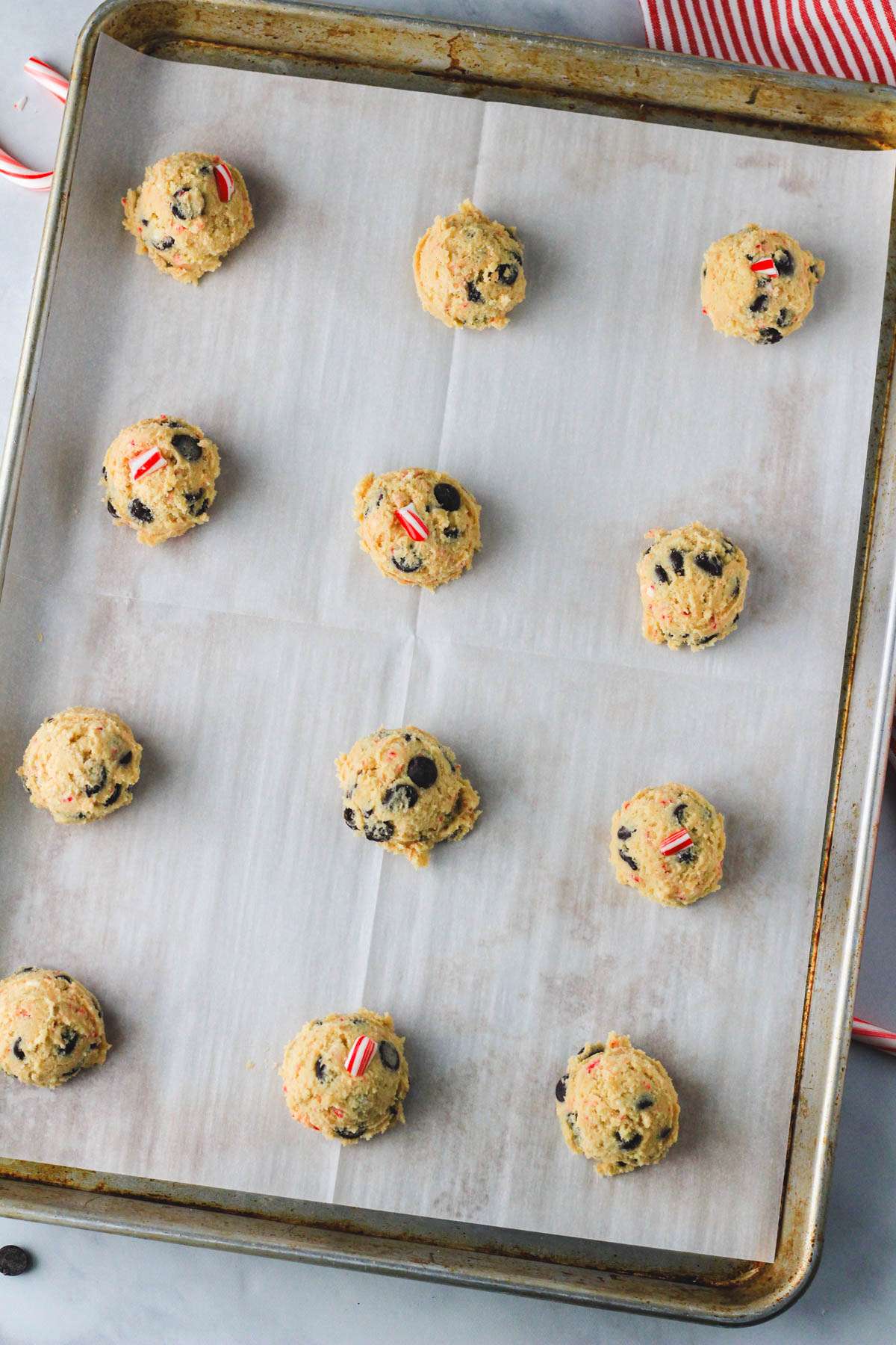 Peppermint chocolate chip cookie dough on a parchment paper lined baking sheet before baking.