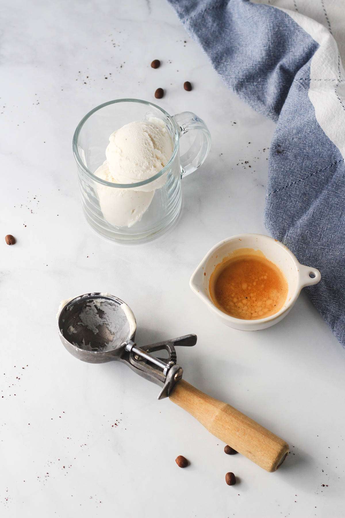Vegan ice cream in a clear cup with a shot of espresso to the right and an ice cream scoop in the bottom left.