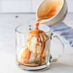 A close up of a glass mug with vegan vanilla ice cream with a shot of espresso being poured on top.