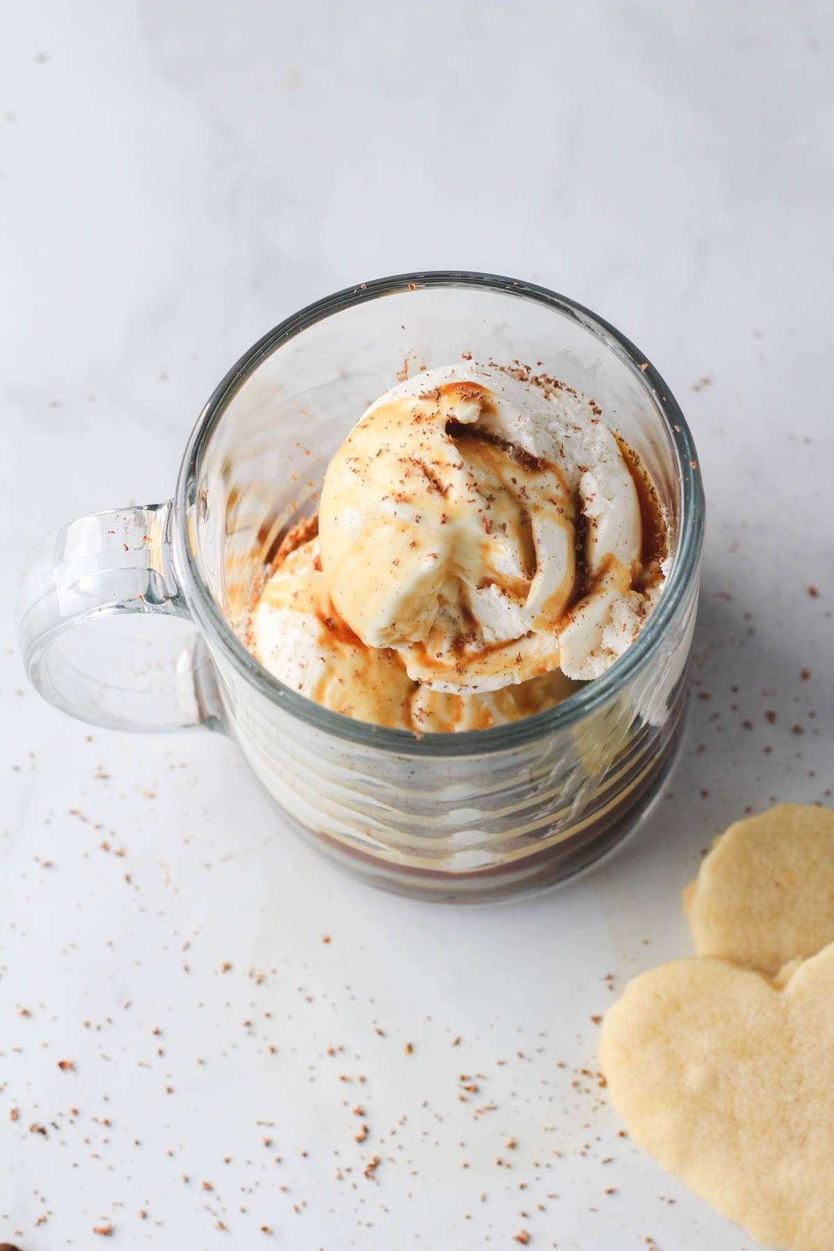 A top down shot of a vegan affogato topped with vegan chocolate and sugar cookies in the bottom right.