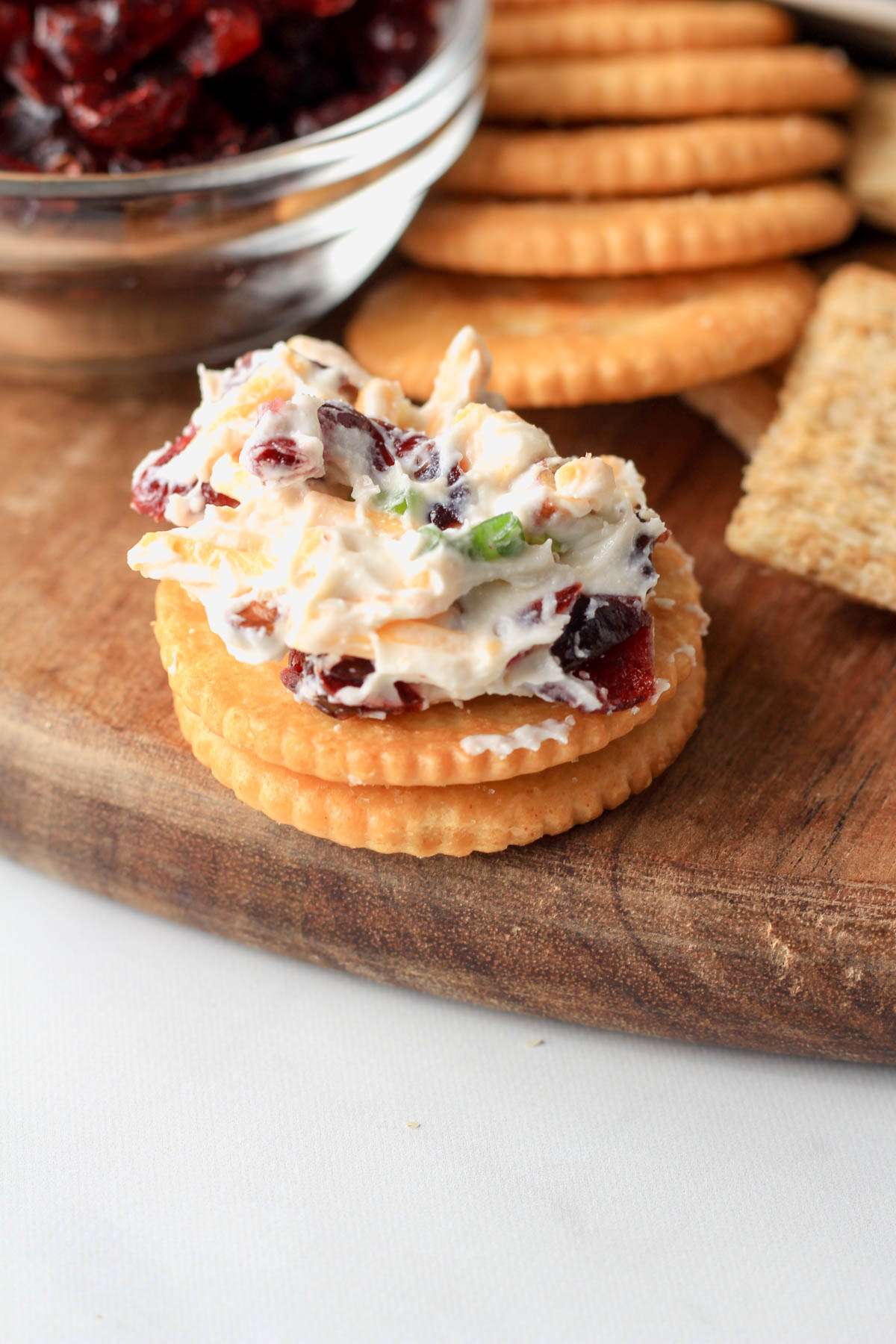 A stack of two Ritz crackers with the top one topped with vegan holiday cheese ball spread.