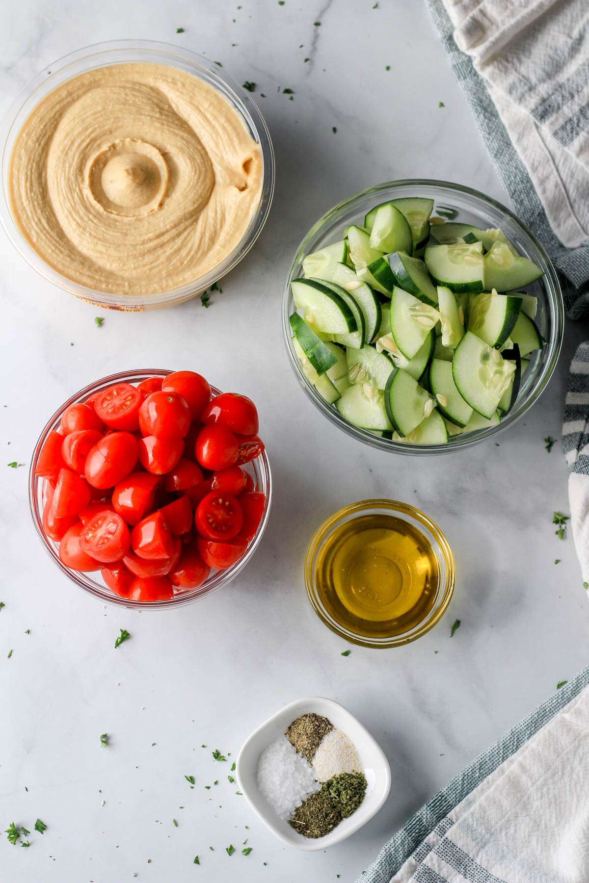 Ingredients for vegan hummus bowl on a white counter.