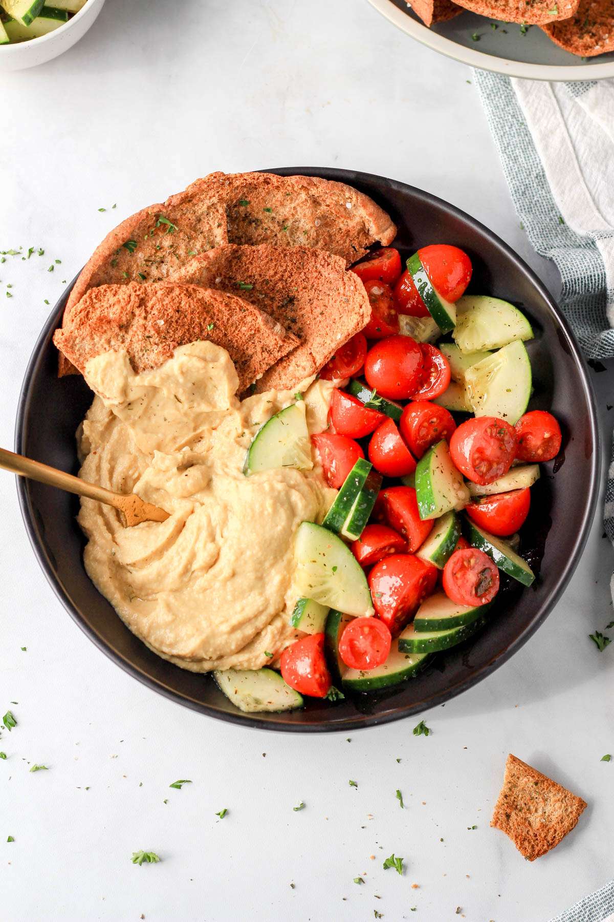 A creamy vegan hummus bowl in a shallow black bowl on a white counter.