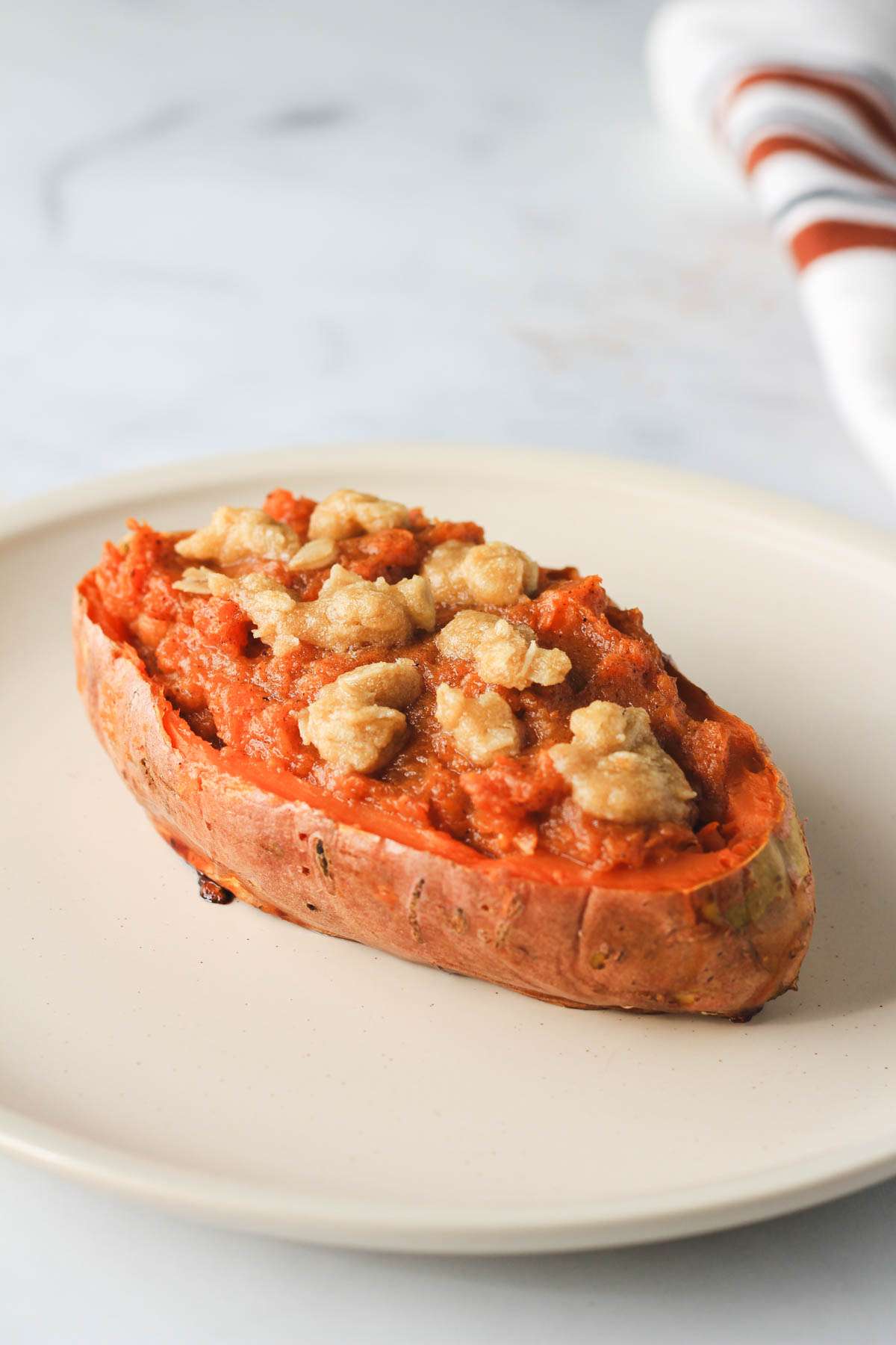 A white plate with one vegan twice baked sweet potato from the side.