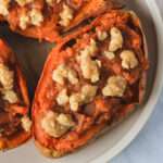 A close up of a vegan twice baked sweet potato on a white plate.