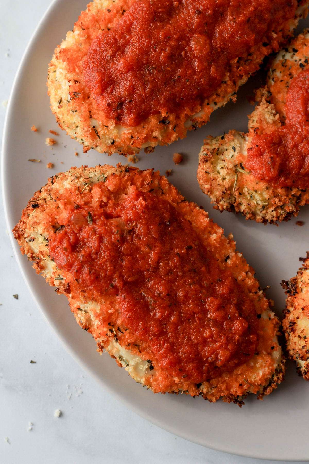 A close up of a chicken breast topped with marinara after cooking in the air fryer.
