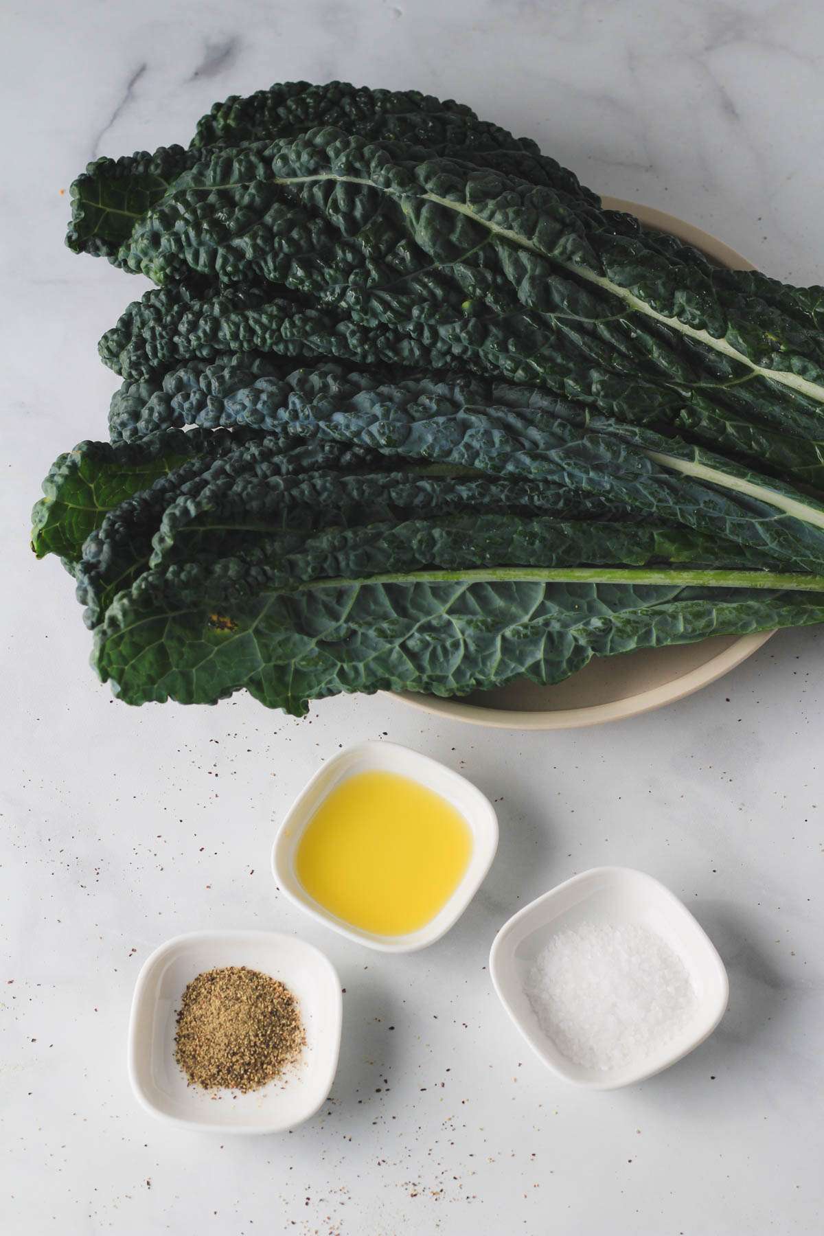 Ingredients for vegan air fryer kale chips on a white counter.