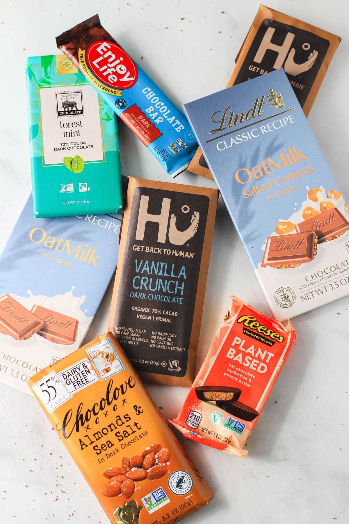An array of dairy-free and vegan chocolate bars on a white counter.